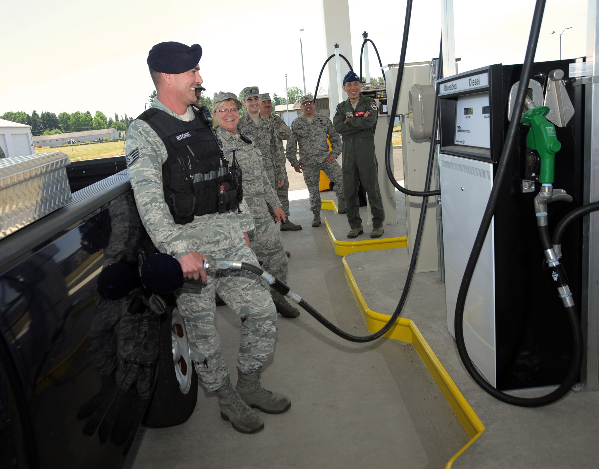 Staff Sgt. Matthew Ritchie, assigned to the 142nd Fighter Wing Security Forces Squadron, left, is the first to fill up at the new on base service station at the Portland Air National Guard Base, June 5, 2014. Other members from the Fighter Wing enjoy the moment along with Col. Jeff Hwang, far right, 142nd Fighter Wing Vice Commander.(Air National Guard photo by Tech. Sgt. John Hughel, 142nd Fighter Wing Public Affairs/Released)