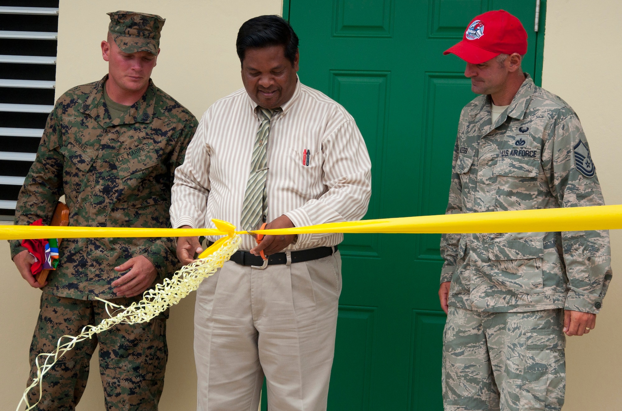 Rodrick Cardinez, Edward P. Yorke school principal, center, cuts the ribbon to officially open the school addition with U.S. Marine Corps Staff Sgt. Matt Houle, construction site foreman, left, and U.S. Air Force Master Sgt. Nicholas Alessi, construction site project manager, right, during the ribbon cutting ceremony June 4, 2014, at the school in Belize City, Belize. The school's 1,372 square foot, two-classroom addition is one of five New Horizons projects constructed in the country. New Horizons is an annual multinational exercise that provides training opportunities in civil engineering and medical care. (U.S. Air Force photo by Tech. Sgt. Kali L. Gradishar/Released)