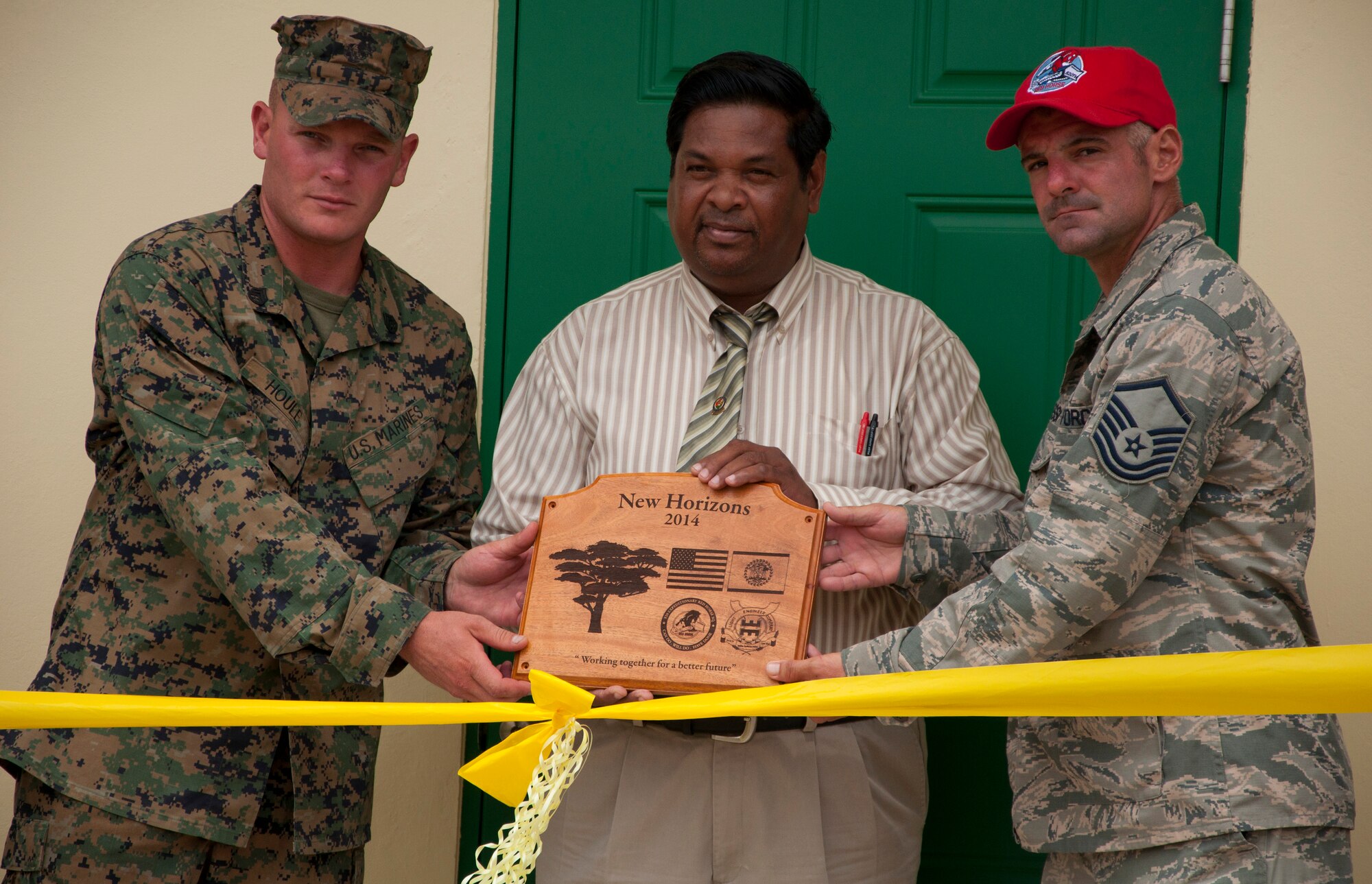 U.S. Marine Corps Staff Sgt. Matt Houle, construction site foreman, left, and U.S. Air Force Master Sgt. Nicholas Alessi, construction site project manager, right, present a plaque to Rodrick Cardinez, Edward P. Yorke school principal, during the ribbon cutting ceremony June 4, 2014, at the school in Belize City, Belize. The school's 1,372 square foot, two-classroom addition is one of five New Horizons projects in the country. New Horizons is an annual multinational exercise that provides training opportunities in civil engineering and medical care. (U.S. Air Force photo by Tech. Sgt. Kali L. Gradishar/Released)
