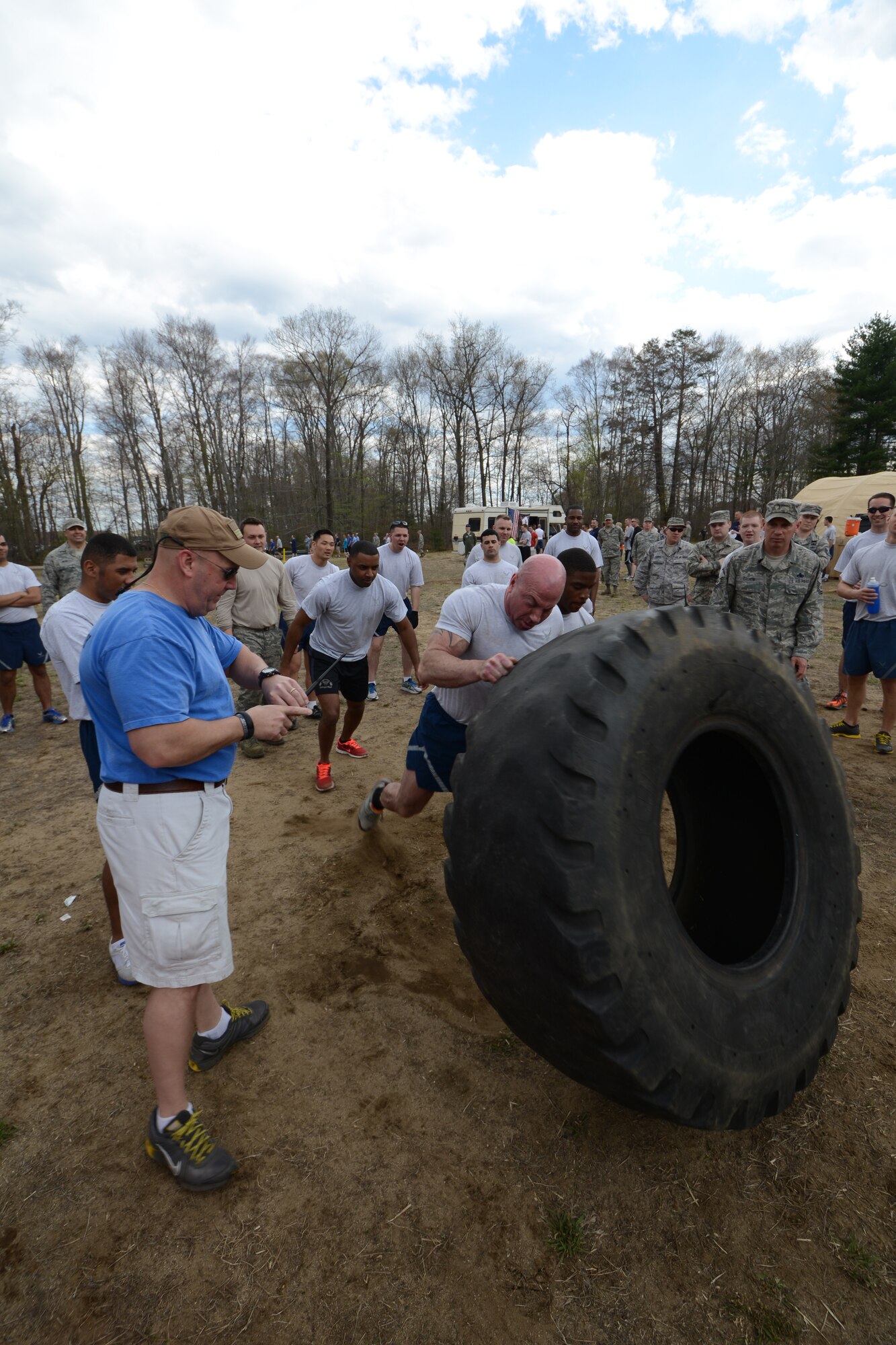 Senior Master Sgt. John Gasiorek keeps a close eye on his watch, tracking the time it takes for the 103rd Maintenance Squadron team, led by Staff Sgt. Davitt Keenan, to flip the massive tractor tire down the course and around the cone. This was a new event added to the second annual Yankee Warrior Day that took place May 3, 2014, at Bradley Air National Guard Base, East Granby, Conn. (U.S. Air National Guard photo by Tech. Sgt. Joshua Mead)