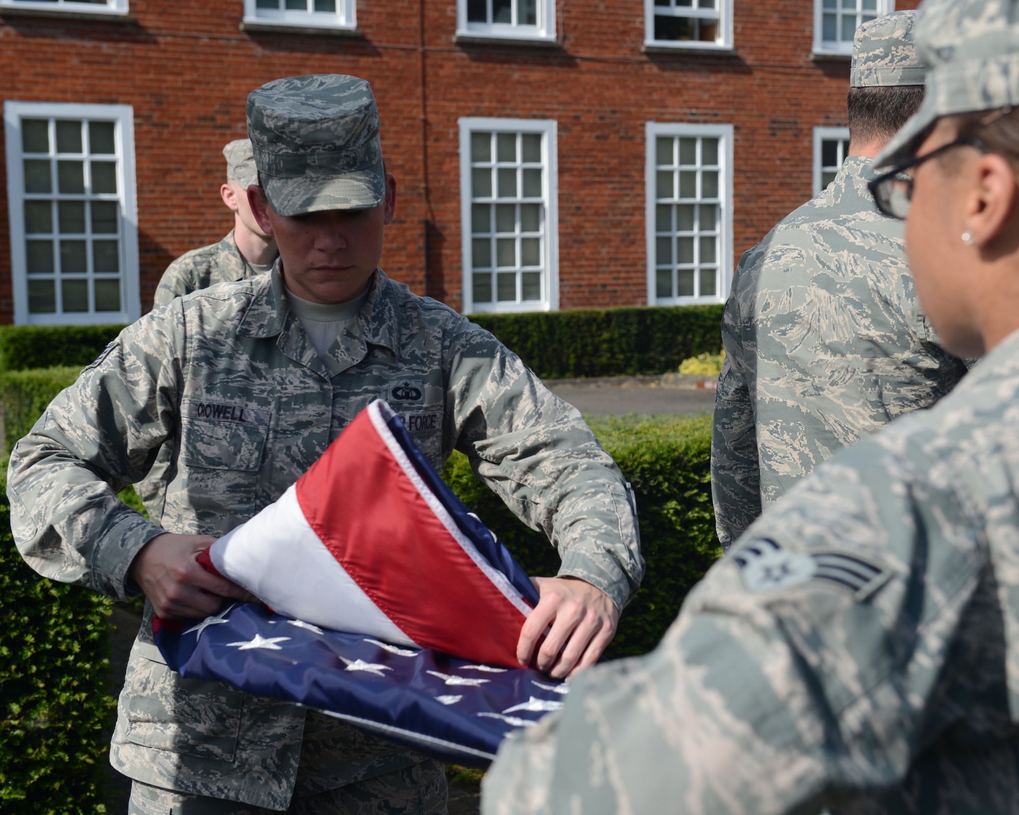Members of a Team Mildenhall flag detail fold the U.S. flag during a retreat ceremony June 6, 2014, on RAF Mildenhall, England. In the time-honored tradition of the retreat ceremony, the U.S. flag and Royal Air Force ensign are folded to signify the end of the duty day. (U.S. Air Force photo/Airman 1st Class Preston Webb/Released)