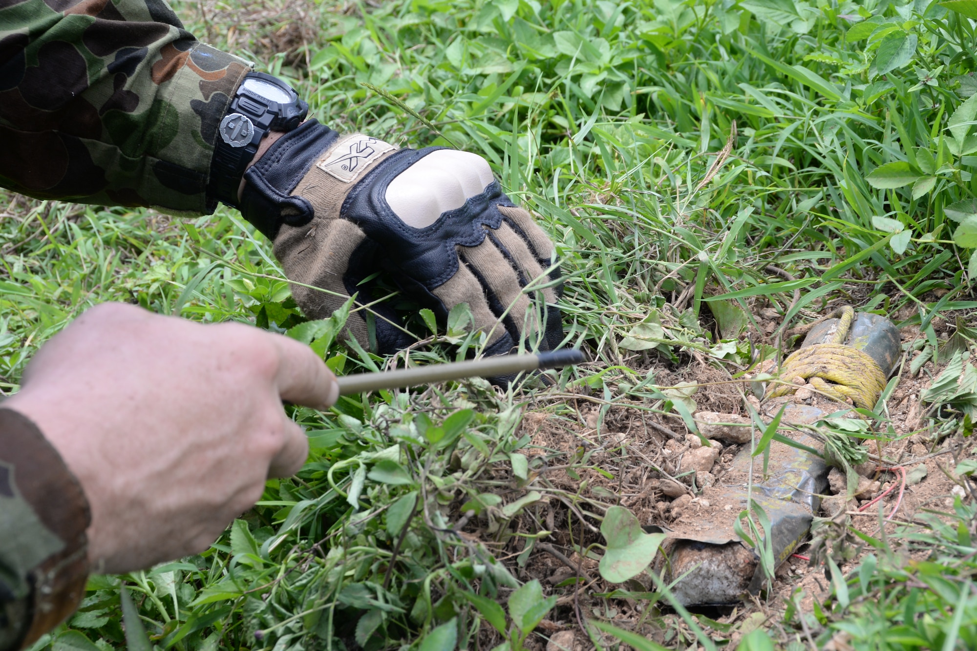 An explosive ordnance disposal technician uncovers a training improvised explosive device during a training event for Exercise Tri-Crab May 5, 2014, on Naval Base Guam. Evaluators set up challenges during the field training exercise, acted as security or witnesses to give the scenarios more detail, and critiqued the technicians. (U.S. Air Force photo by Airman 1st Class Amanda Morris/ Released)