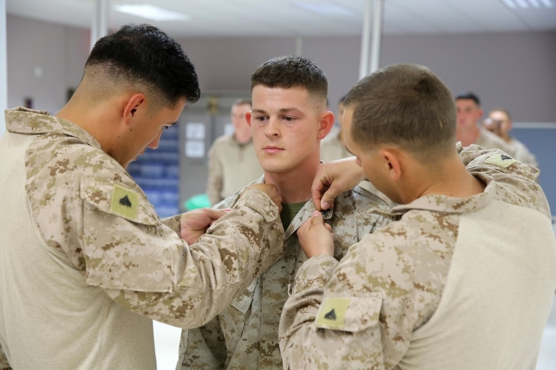 Corporal Jacob Gamble, a native of Oskaloosa, Kansas, stands at attention while Marines pin corporal insignia to his collar during a promotion ceremony aboard Camp Leatherneck, Afghanistan, June 1, 2014. Gamble, a field radio operator with Headquarters and Service Company, 1st Battalion, 7th Marine Regiment, and 20 other lance corporals with the battalion were promoted to corporal, June 1 and 2. (U.S. Marine Corps photo by Cpl. Joseph Scanlan / released)