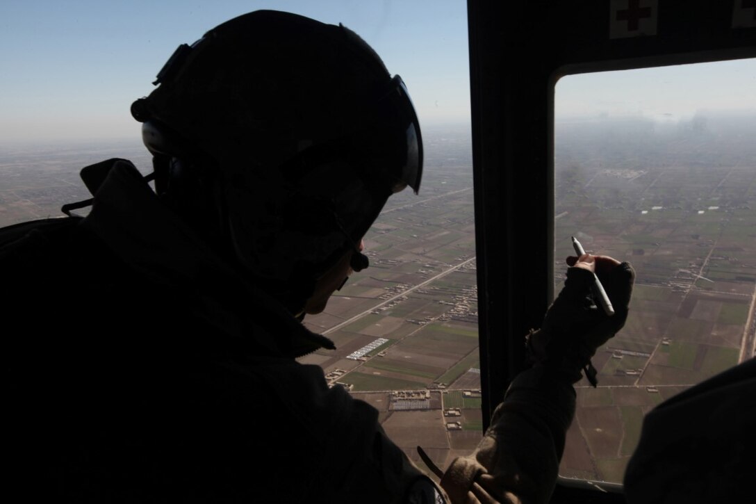Corporal David Smith, a UH-1Y Huey crew chief with Marine Light Attack Helicopter Squadron 369, and a Harrisburg, Pa., native, writes down coordinates while in flight over Helmand province, Afghanistan, Feb. 15, 2014. The mission of HMLA-369 varies from offensive air support, utility support and armed escorts, all day or night. (U.S. Marine Corps Photo illustration By: Sgt. Frances Johnson/Released)
