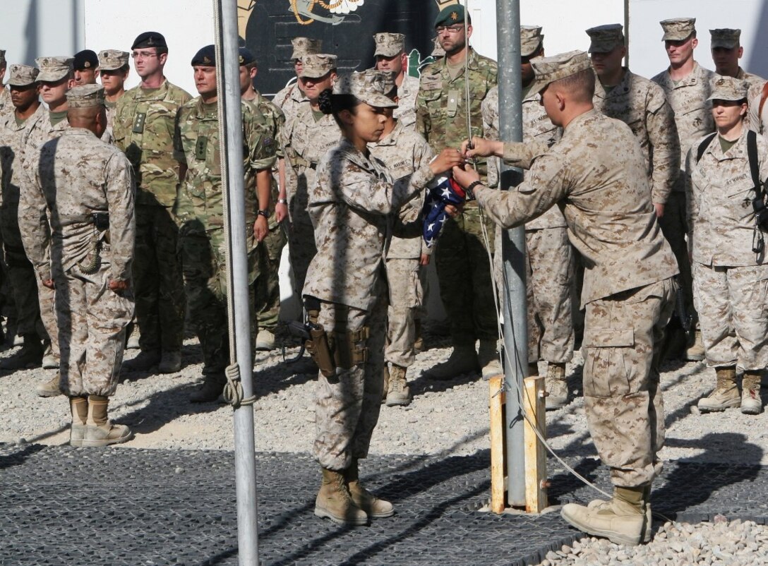Sergeant Elizabeth Pineda, left, administrative noncommissioned officer in charge, and Sgt. Kyle Bond, commanding general personal security detail, prepare to raise the American flag during a Memorial Day ceremony aboard Camp Leatherneck, Afghanistan, May 26, 2014. During the ceremony, RC(SW) Commander Brig. Gen. Daniel D. Yoo spoke about the importance of the day and service members observed a moment of silence to remember those who gave their lives in service to their country. (U.S. Marine Corps photo by Cpl. Cody Haas/ Released)
