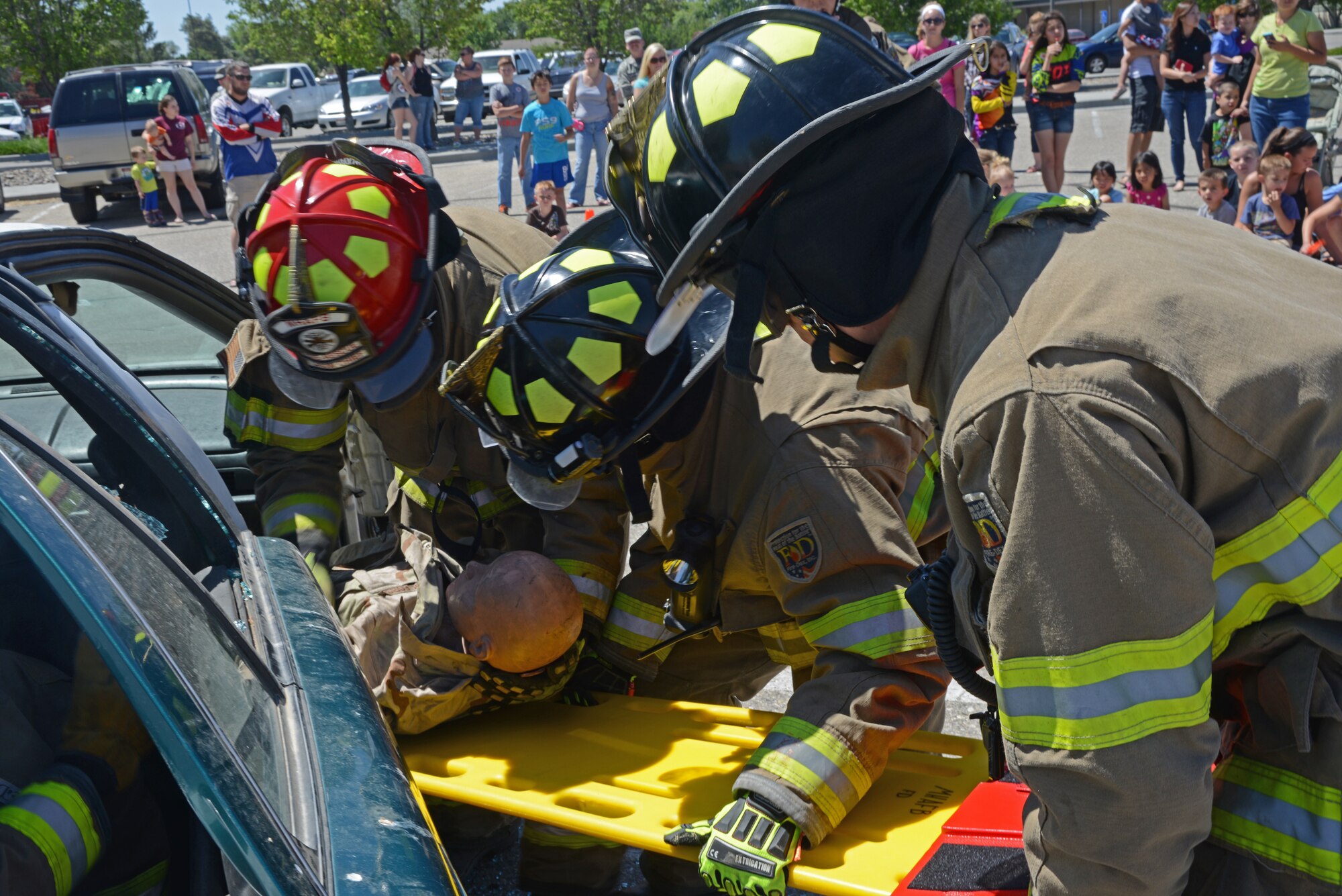Firefighters from the 366th Civil Engineering Squadron remove a training dummy from a vehicle during a training scenario at the Mountain Home AFB safety fair June 6, 2014, at Mountain Home Air Force Base, Idaho. Members of the Gunfighter community witnessed the firefighters simulate a car crash's life-saving training techniques. (U.S. Air Force photo by Senior Airman Benjamin Sutton/Released)