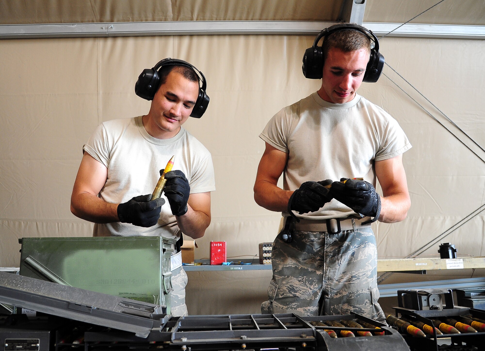 U.S. Air Force Airman 1st Class David Duston, left, and Airman 1st Class Jeremy Gomez, both munitions crew members, inspect 20 mm rounds during Exercise Eager Lion June 4, 2014, at an air base in northern Jordan. Both Airmen are from the 35th Maintenance Squadron at Misawa Air Base, Japan, and are providing munitions support during the exercise for F-16 Fighting Falcons also from Misawa. (U.S. Air Force photo by Staff Sgt. Brigitte N. Brantley/Released)