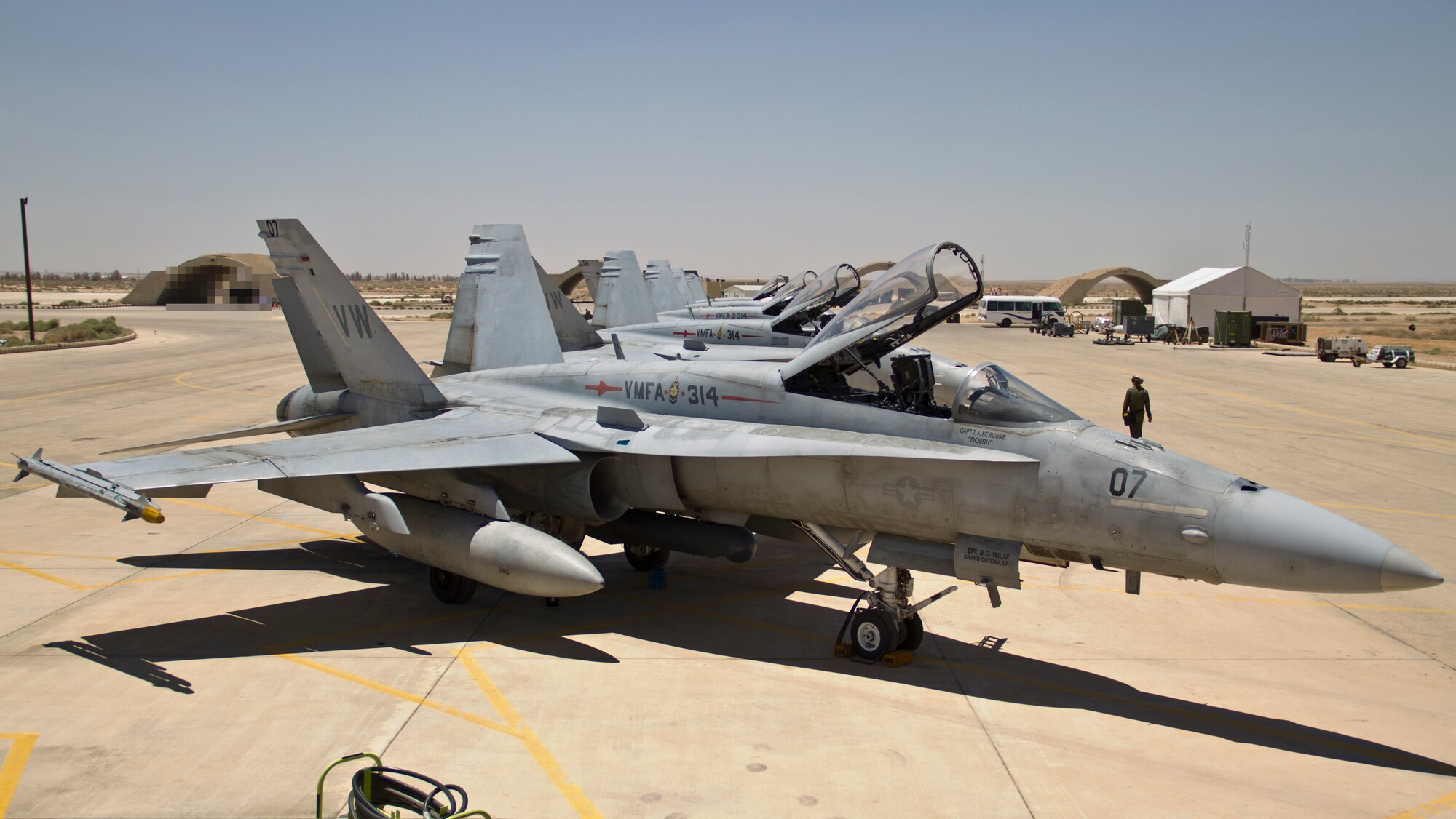 A row of U.S. Marine Corps F-18 Hornets from Marine Fighter Attack Squadron 314 at Marine Corps Air Station Miramar, Calif., await post-flight maintenance during Exercise Eager Lion June 11, 2014, at an air base in northern Jordan. This year, more than 12,500 personnel from more than 20 nations are participating in the exercise, which is designed to strengthen military-to-military relationships and interoperability. (U.S. Air Force photo by Staff Sgt. Tyler McLain/Released/Background blurred for security purposes.)