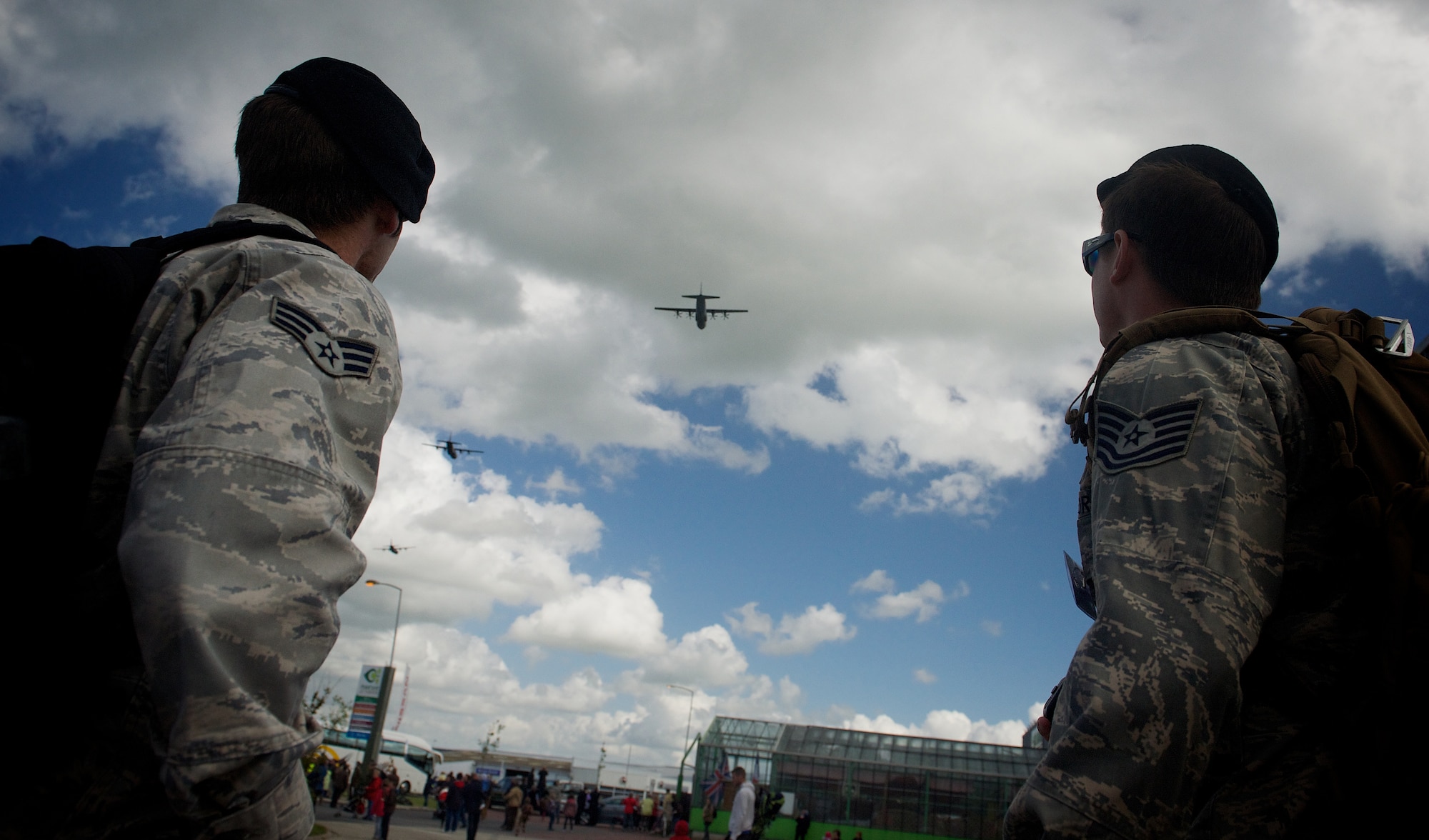 Tech. Sgt. Zachary Jacobs, right, and Senior Airman Jason Hoff watch as C-130 Hercules perform a ceremonial flyover at a 70th D-Day anniversary memorial event, June 4, 2014, in Carentan, France. Jacobs and Hoff are joint terminal attack controllers with the 116th Air Support Operations Squadron, Wash., assigned to Normandy to coordinate air movements during the events celebrating the liberation of Normandy by allied troops in 1944. (U.S. Air Force photo/Senior Airman Alexander W. Riedel)