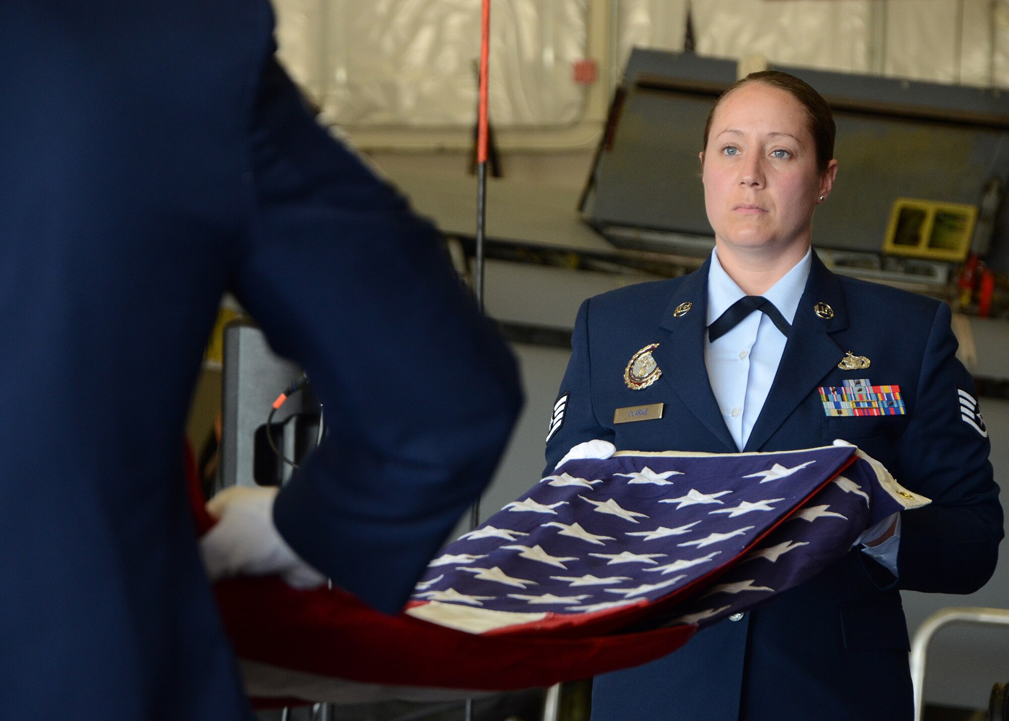 PEASE AIR NATIONAL GUARD BASE, N.H. -- Staff Sgt. AutumnRose Clarke folds the flag during a flag folding ceremony in recognition of Chief Master Sgt. Brenda Blonigen's retirement ceremony in Hanger 254 here, June 7. Blonigen retired after 34 years of service on active duty and the Air National Guard. (U.S. Air Force photo by Tech. Sgt. Mark Wyatt)