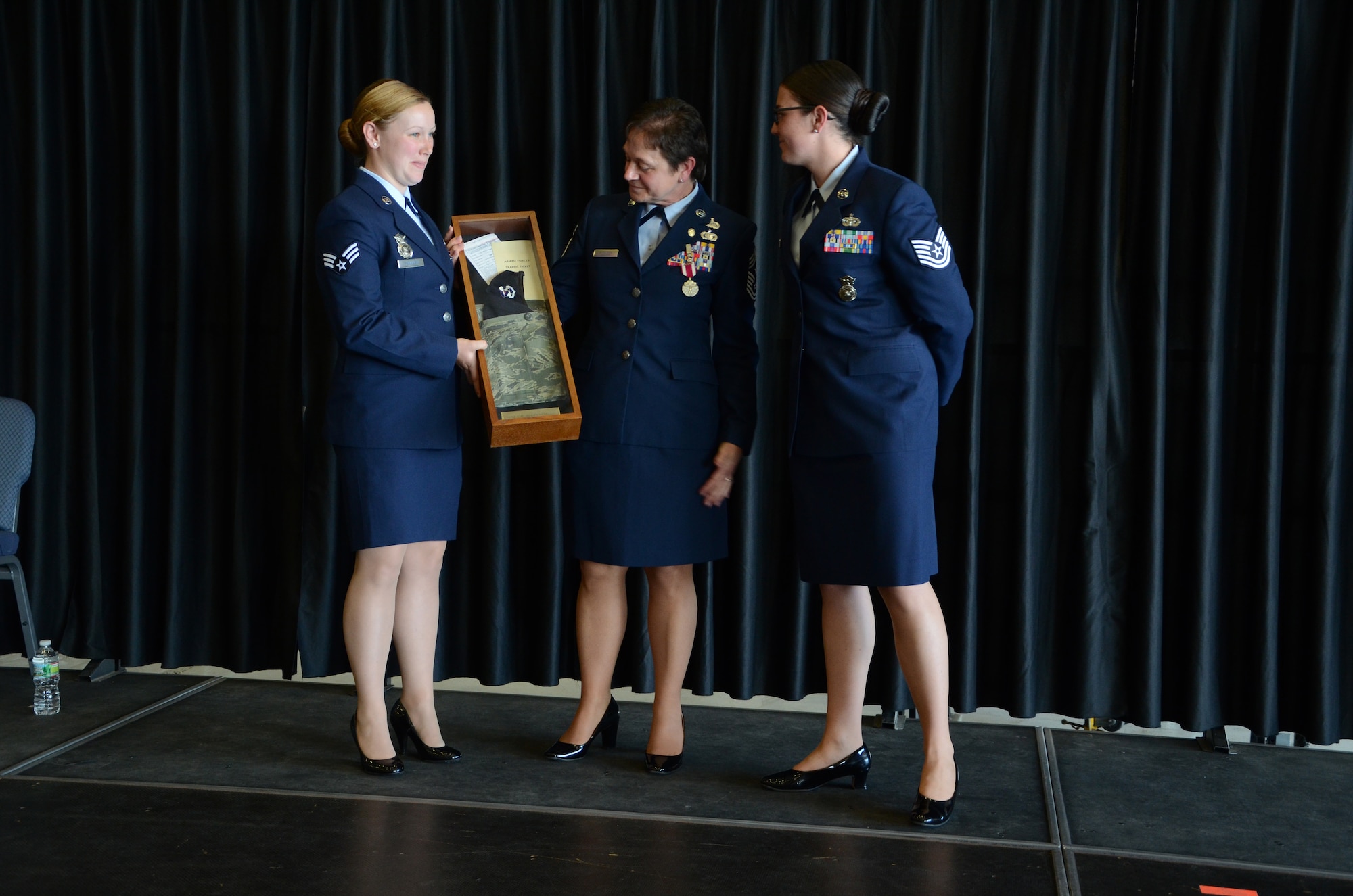 PEASE AIR NATIONAL GUARD BASE, N.H. -- Senior Airman Kelsey Hannafin and Tech. Sgt. Kristina Johnson, both members of the 157th Security Forces Squadron, make a presentation to Chief Master Sgt. Brenda Blonigen during a retirement ceremony in Hanger 254 at Pease Air National Guard Base June 7. The presentation was made to recognize the chief as a former security police member. (U.S. Air Force photo by Tech. Sgt. Mark Wyatt)