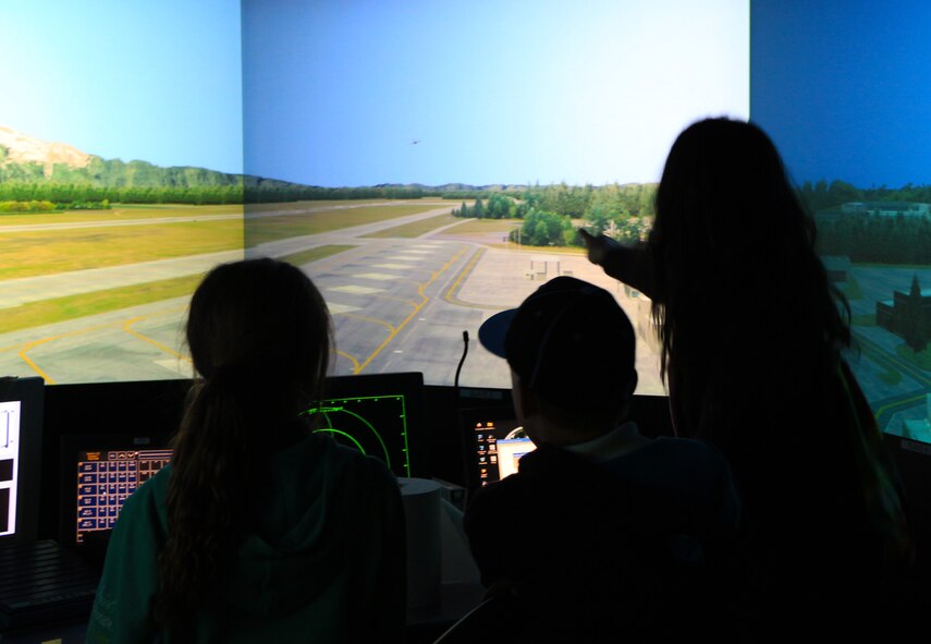 A member and family members of the Women in Aviation Washington Chapter watch as a C-17 Globemaster III takeoff is simulated on the air traffic control simulator at McChord Field June 7. The group was able to ask air traffic controllers about the many aspects of their jobs. (U.S. Air Force Reserve photo by Senior Airman Madelyn McCullough)