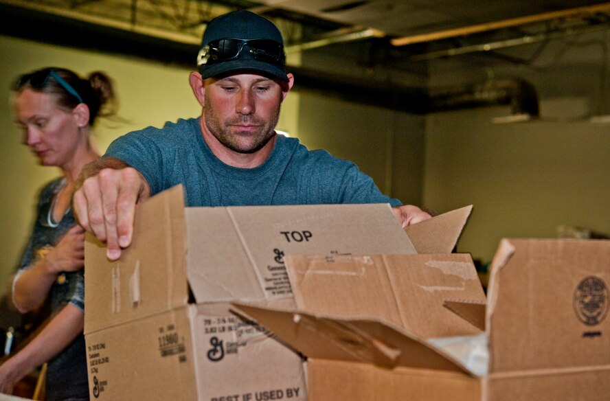 Master Sgt. Cory McGee, 509th Civil Engineer Squadron firefighter, fills boxes for care packages at the Warrensburg United Way June 7, 2014, in Warrensburg, Mo. About 100 boxes were filled for care packages to send to deployed members of the 442nd Fighter Wing. (U.S. Air Force photo by Senior Airman Daniel Phelps/Released)