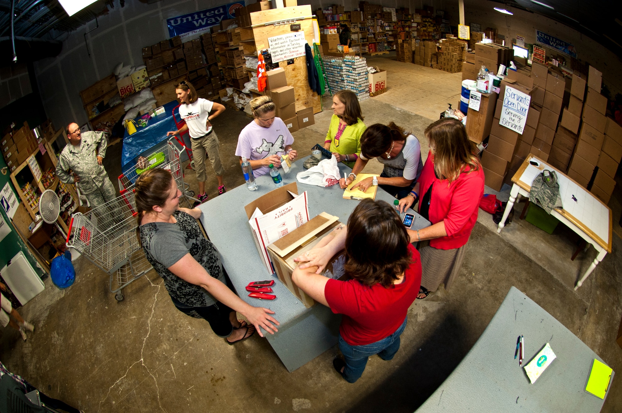 Members of the 442nd Fighter Wing and Key Spouses club discuss logistics for the care packages at the Warrensburg United Way June 7, 2014, in Warrensburg, Mo. Boxes were filled for care packages to send to deployed members of the 442nd Fighter Wing. (U.S. Air Force photo by Senior Airman Daniel Phelps/Released)