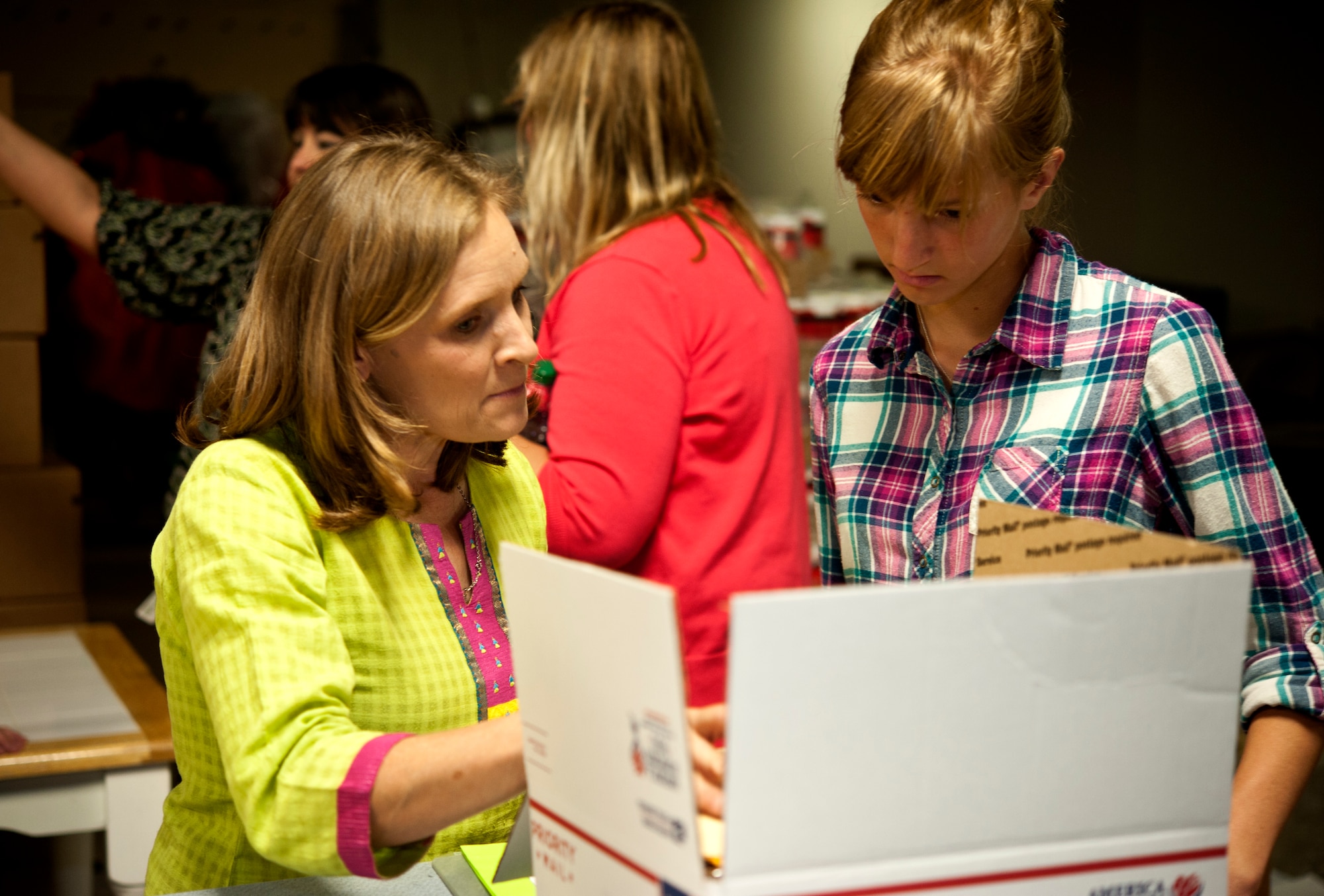 Rhonda Smith, wife of Col. Paul Smith, 442nd Medical Group commander, and Kennedi McGee, daughter of Staff Sgt. Larissa McGee, 442nd Logistics Readiness Squadron, and Master Sgt. Cory McGee, 509th Civil Engineer Squadron, review a care package at the Warrensburg United Way June 7, 2014, Warrensburg, Mo. Boxes were filled for care packages to send to deployed members of the 442nd Fighter Wing. (U.S. Air Force photo by Senior Airman Daniel Phelps/Released)