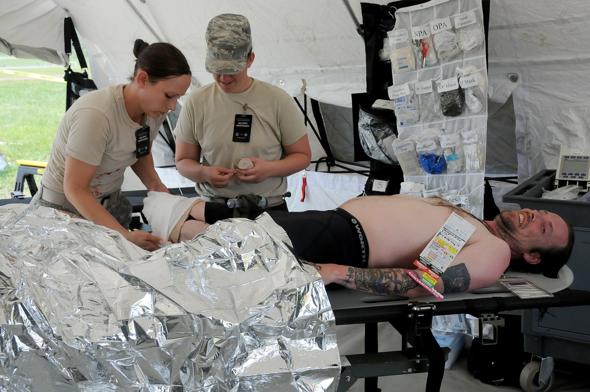 Army Sgt. Ashleigh Hass, VA Medical Command at Fort Pickett combat medic (left), and Airman 1st Class Holly Roberts, 192nd Fighter Wing Medical Group medical technician (right), bandage a “patient’s” amputated leg, during the Vigilant Guard exercise in which the 192nd MDG participated in to enhance their Chemical, Biological, Radiological, Nuclear, and Explosive (CBRNE) Enhanced Response Force Package (CERFP) training, at Fort Indiantown Gap, Pa., May 13, 2014. The CERFP conducts tasks associated with incident management, search and rescue, mass casualty decontamination, medical triage, and fatality recovery. (U.S. Air National Guard photo by Airman 1st Class Johnisa B. Roberts/Released)