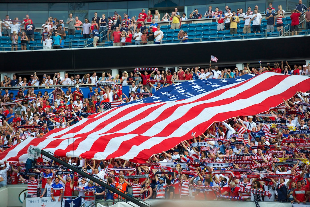 Service members hold the U.S. flag in the stands as fans sing the national anthem before the U.S.-Nigerian soccer match at Everbank Field, Jacksonville, Fla., June 7, 2014.