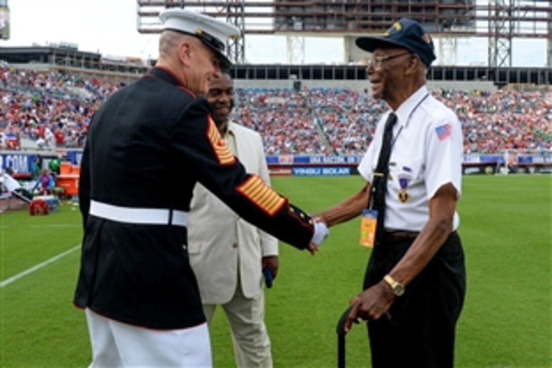 Marine Corps. Sgt. Maj. Bryan B. Battaglia, senior enlisted adviser to the chairman of the Joint Chiefs of Staff, shakes hands with Samuel Muldrew, right, a World War II veteran and Purple Heart recipient, during halftime at the U.S.-Nigerian soccer match at Everbank Field, Jacksonville, Fla., June 7, 2014. Alvin Brown, center, mayor of Jacksonville, Fla., looks on. 