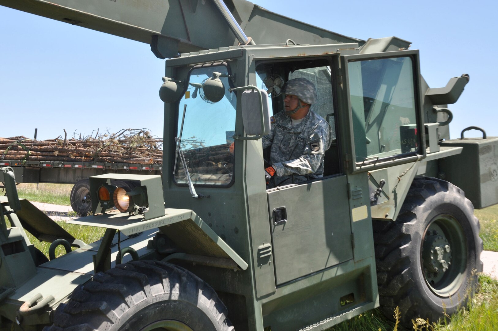 Sgt. Marcus Martin, a member of the 152nd Combat Sustainment Support Battalion operates a forklift while unloading timber from a flatbed trailer in his hometown of Wanblee, S.D., as part of a timber haul mission during exercise Golden Coyote, June 16, 2012. The mission delivered humanitarian aid in the form of timber to be used by his local Native American communities for heating and ceremonial purposes.