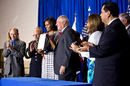 First Lady Michelle Obama holds the "Military Family Licensing Act," which will help military spouses and veterans transfer their professional licenses to Illinois more easily, during a signing ceremony in Chicago, June 26, 2012. Illinois Gov. Pat Quinn, to the right of the First Lady, signed the act.