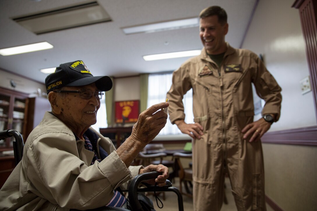 Charles Masakatsu Tanaka, a 96-year-old WWII veteran, receives a station patch and challenge coin from Col. Robert V. Boucher, Marine Corps Air Station Iwakuni, Japan, commanding officer, aboard station, June 6, 2014. Tanaka served in the United States Army from 1941-1945 with the 100th Infantry Battalion. His battalion served in the European Theater and was first sent to South Africa, where they later entered combat in Italy. He was hit by shrapnel from an artillery shell in his right leg, which disabled him and was later medically separated. Tanaka received two Bronze Stars, a Purple Heart and the Congressional Gold Medal; the highest civilian award bestowed by the U.S. Congress.
The 100th Infantry Battalion is now the only remaining infantry unit in the Army Reserve force structure. Its headquarters is still located in Hawaii and it is the most decorated battalion in U.S. Army history. 
Tanaka currently resides in Hawaii, but took a vacation to see his family grave site in Kumamoto, Japan. While in the area, he wanted to visit an American base to see the relationship between Japanese and Americans. 
“I really like this air station,” said Tanaka. “There’s Japanese people all around you folks, and all I see is harmony. That’s what I’m looking for. That’s what I fought for.” 