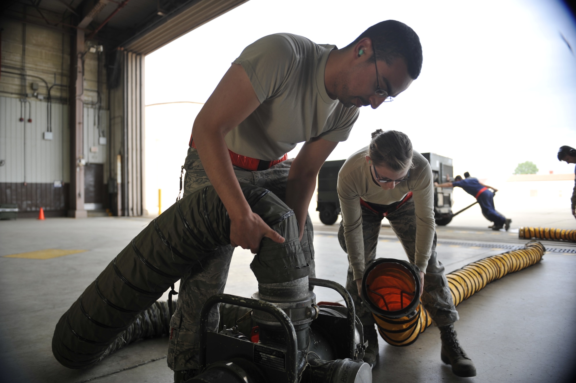 Senior Airman Ashton Terry, left, and Senior Airman Andreana Chilcott, 5th Reconnaissance Squadron crew chiefs, unhook the cooling hoses from a U-2 Dragon Lady on Osan Air Base, Republic of Korea, June 5, 2014. The hoses help prevent the aircraft systems from overheating. (U.S. Air Force photo/Senior Airman David Owsianka)