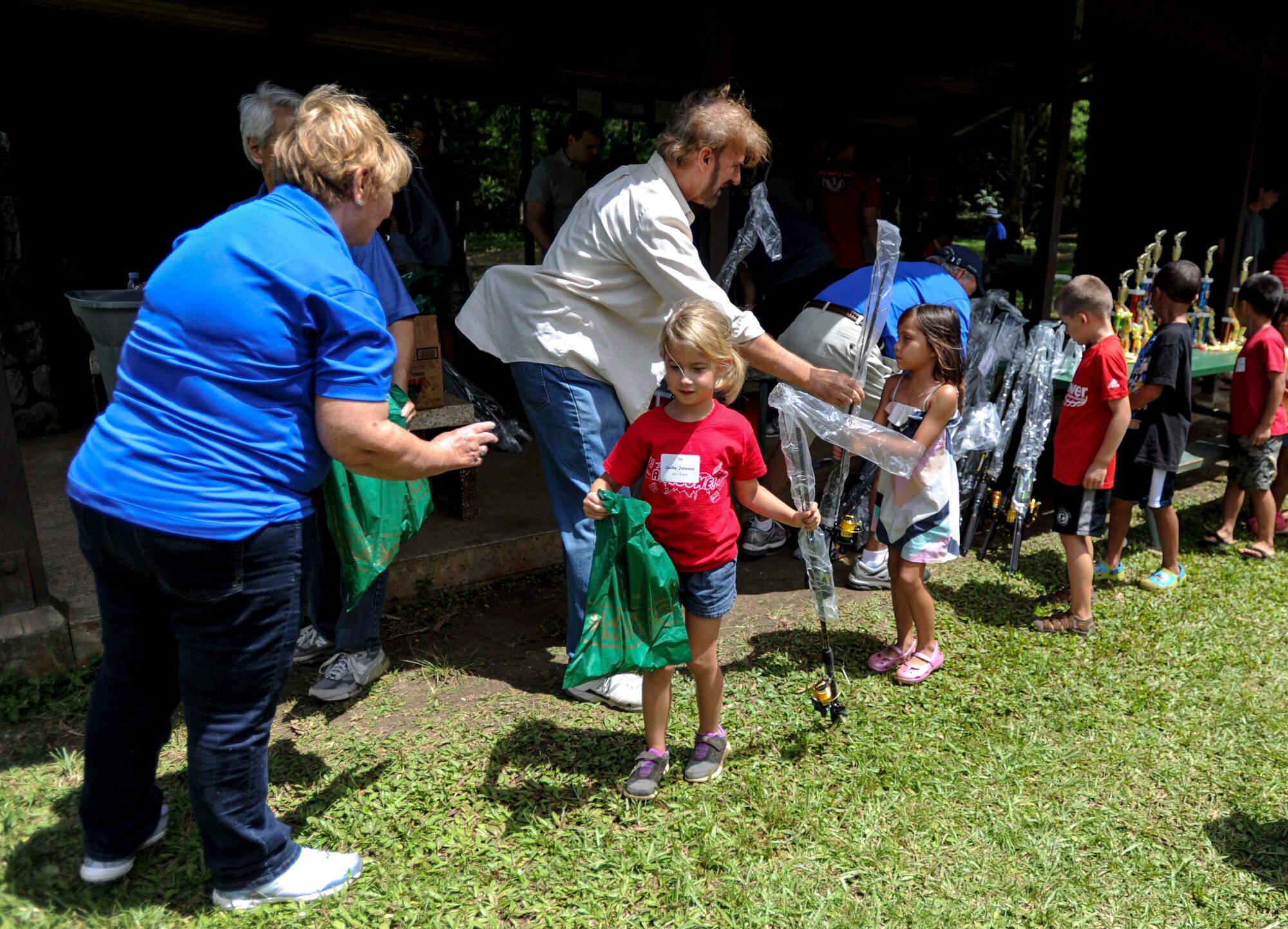 Members and volunteers from the Friends of Hickam organization hand out goody bags and fishing poles to Hickam Keiki after the 15th Annual Keiki Fishing Tournament at the Ho’omaluhia Botanical Garden in Kaneohe, Hawaii, June 4, 2014. More than 120 children and parents were in attendance of the free event hosted by the Friends of Hickam organization to support, promote and foster strong community relations with military families. (U.S. Air Force photo/Tech. Sgt. Terri Paden)