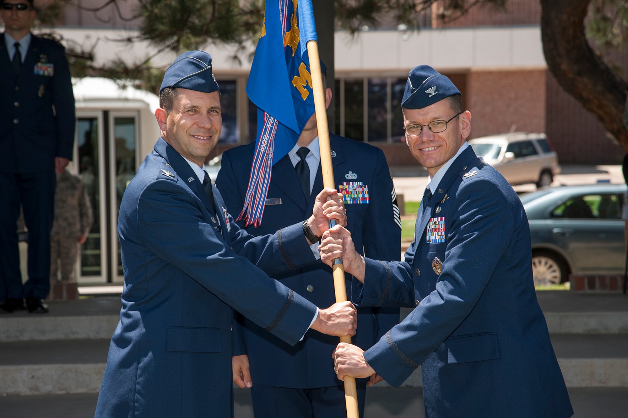 PETERSON AIR FORCE BASE, Colo. -- Col. John Shaw, 21st Space Wing commander, passes the 21st Mission Support Group guidon to Col. Reginald Ash III during the 21st MSG change of command at the base parade grounds June 2. As the new 21st MSG commander, Ash will be responsible for providing civil engineering, communications, contracting, logistics, personnel, security and services support to squadrons operating worldwide to execute their missile warning and space control missions. Ash was most recently the senior military advisor for European and Eurasian Affairs at the U.S. Department of State in Washington, D.C. (U.S. Air Force photo/Craig Denton)