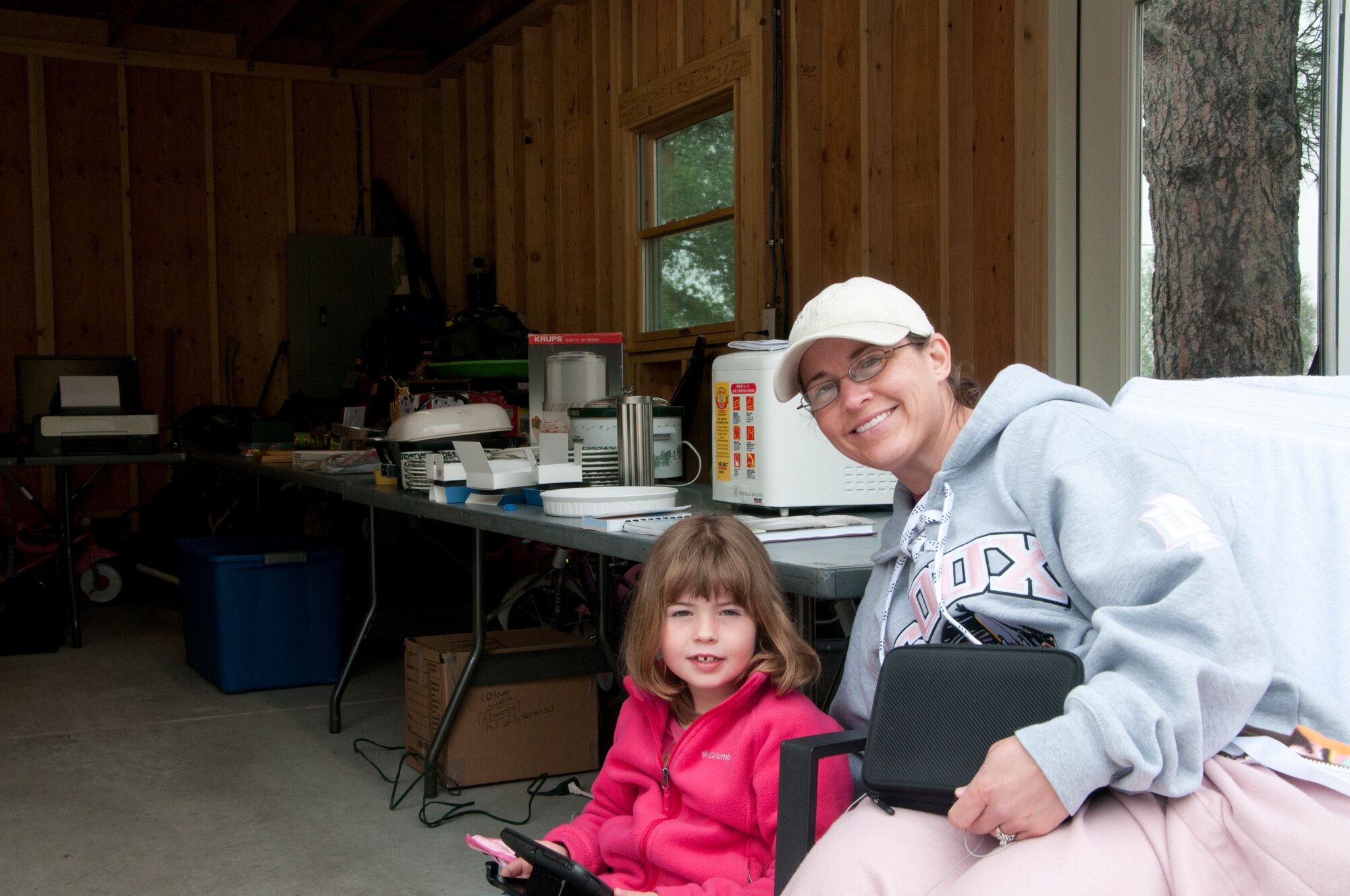 Lieutenant Col. Cynthia Gunderson, 321st Missile Squadron commander, and her daughter Kylie, pose outside their garage in which the Gundersons set up items for sale for F.E. Warren Air Force Base Yard Sale June 7, 2014. (U.S. Air Force photo by Airman 1st Class Jason Wiese)