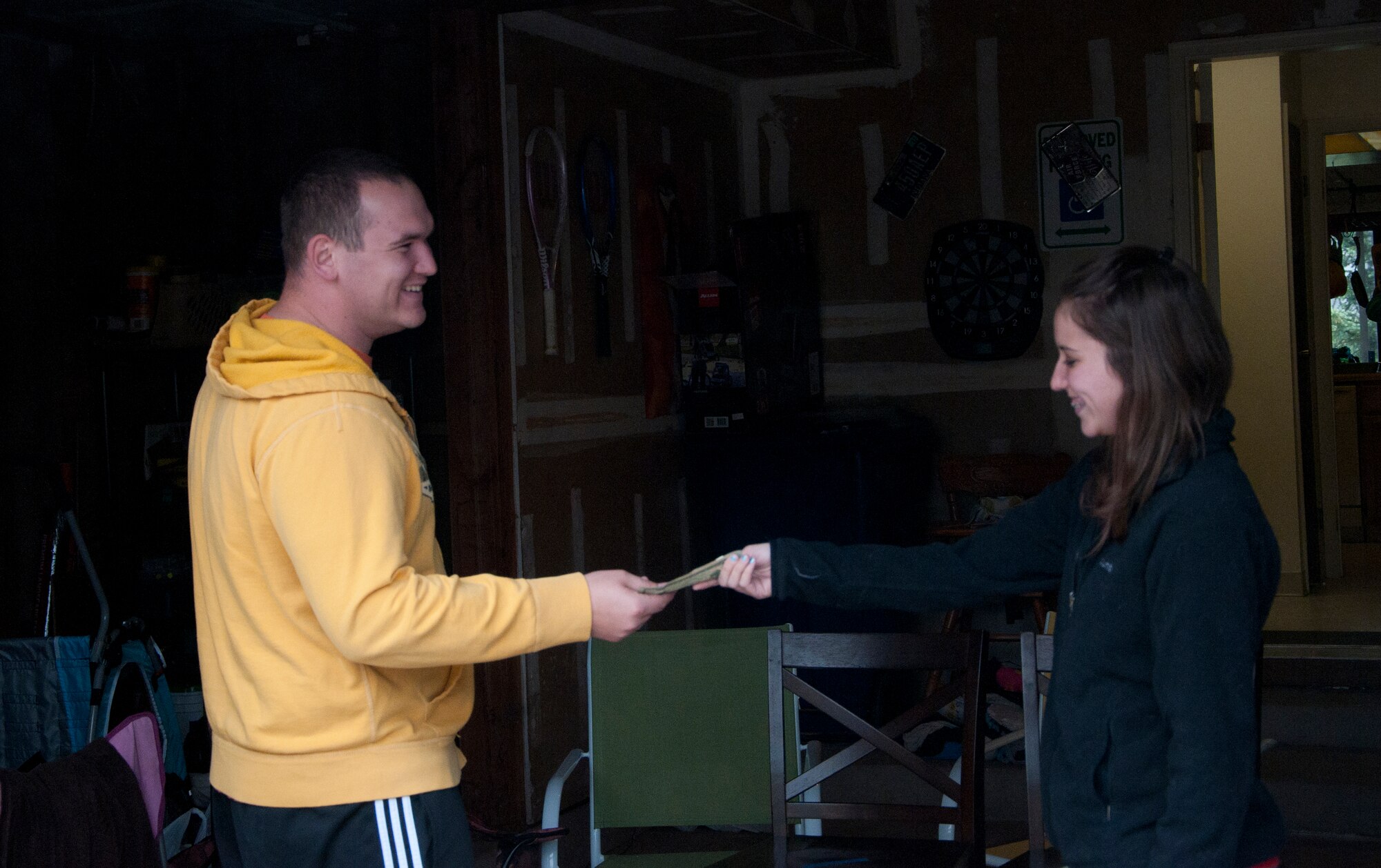 Emily Bates, wife of Senior Airman Bryce Bates, 90th Security Forces Group Personnel Reliability Program manager, pays Senior Airman Anthony Heuck, 90th Missile Maintenance Squadron electro-mechanical technician for a Playstation 2 he sold from his garage during the F.E. Warren Air Force Base Yard Sale June 7, 2014. (U.S. Air Force photo by Airman 1st Class Jason Wiese)