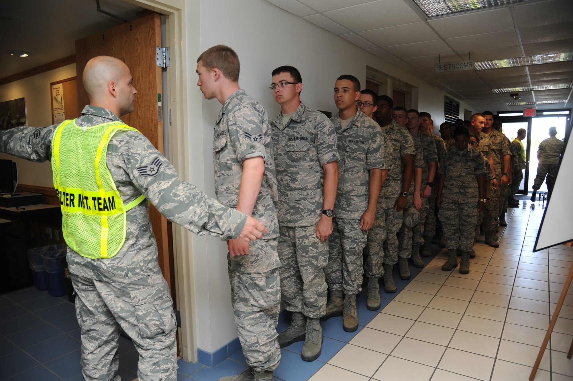 Staff Sgt. Brandon Alvarez, 335th Training Squadron and shelter management team member, guides Airmen into a room to complete hurricane shelter in-processing forms during a hurricane exercise June 6, 2014, at Allee Hall, Keesler Air Force Base, Miss.  The purpose of the exercise was to prepare Keesler for the current hurricane season.  (U.S. Air Force photo by Kemberly Groue)