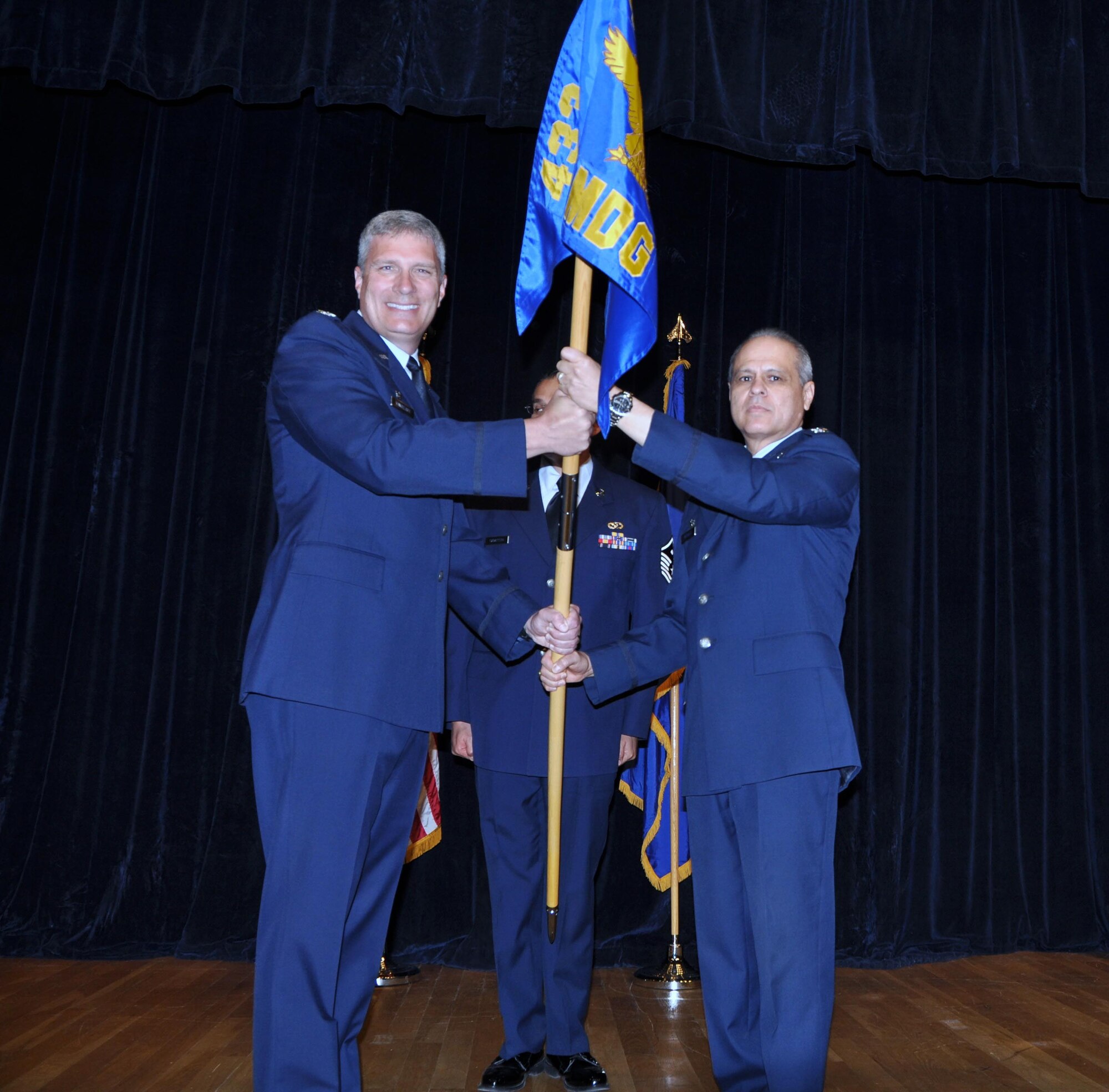 Col. Aaron Vangelisti (left), 433rd Airlift Wing commander, passes the guide on of leadership  for the 433rd Medical Group  to Col. Ernest Vasquez on May 4, 2014 at the Wilford Hall Auditorium on Joint Base San Antonio-Lackland, Texas. 