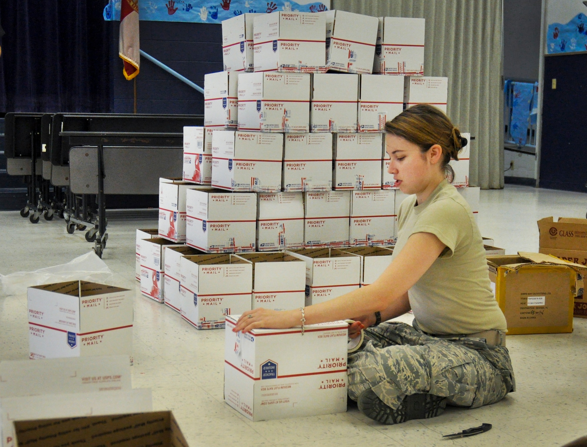 2nd Lt. Victoria Carrillo, from the 86th Fighter Weapons Squadron, builds boxes at the Eglin Elementary School cafeteria during the troop care drive June 6.  The Company Grade Officer’s Council collected 216 handwritten letters and drawings from Destin Elementary School students.  These letters and drawings were included in the care packages along with sundry comfort items.  The items were donated by the CGOC, who also hosted the event.  Volunteers packed a total of 108 care packages for Eglin’s deployed.  (U.S. Air Force photo/Ilka Cole)