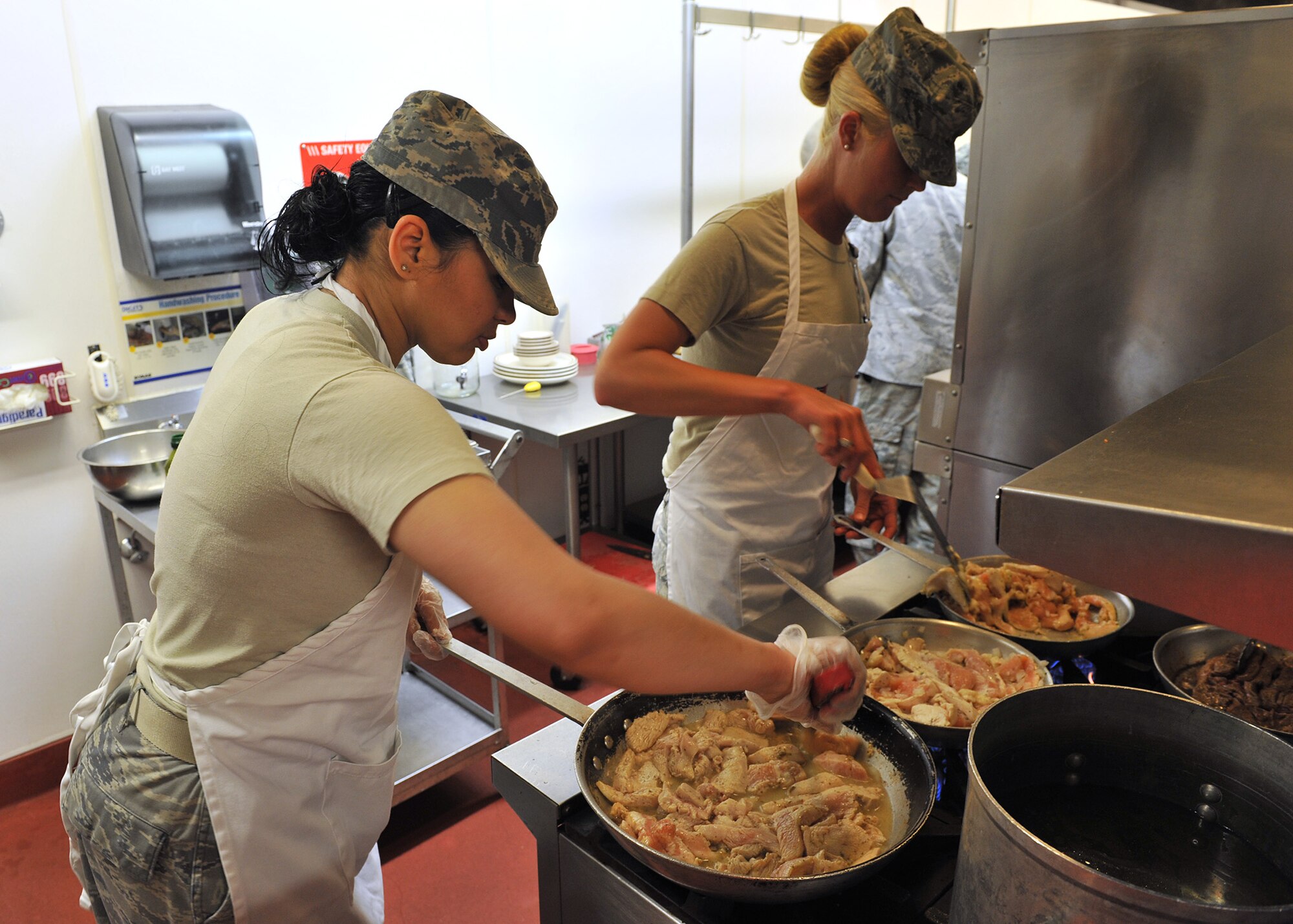 Staff Sgt. Hangie De Los Santos, alpha flight team (left) and Staff Sgt. Jessica Pasch, charlie flight team, prepare chicken June 3 for their Warrior Chef entrées. Both are from the 341st Force Support Squadron. (U.S. Air Force photo / John Turner)
