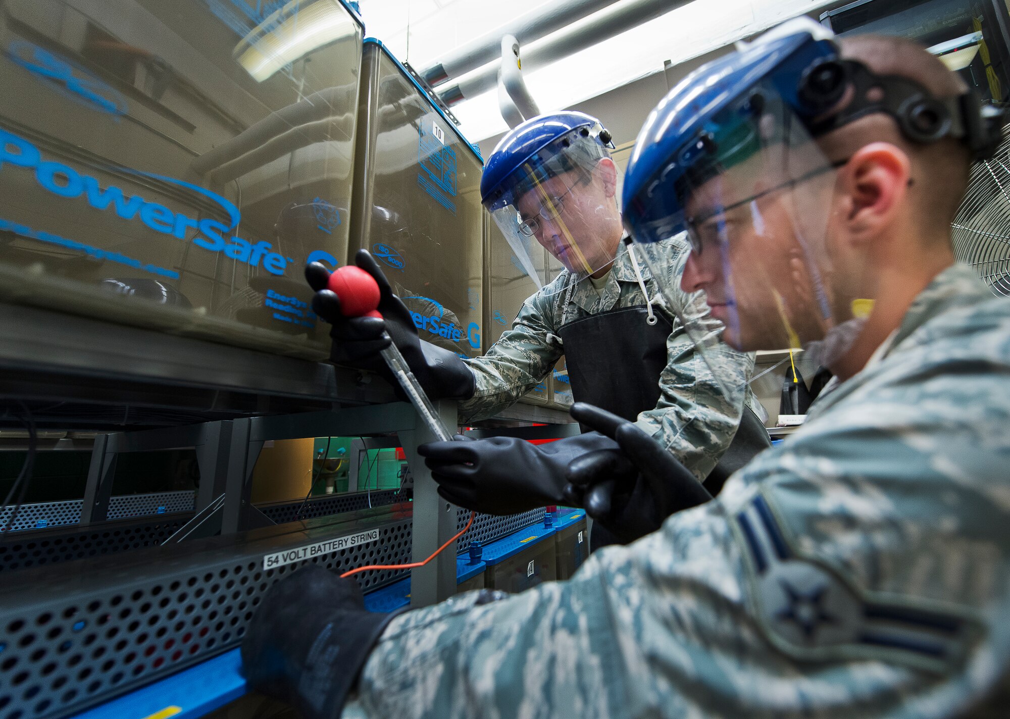 Senior Airman Michael Detwiler and Airman 1st Class Logan Robbins, of the 96th Communications Squadron’s voice network systems, measure the acid level in a backup battery with a hydrometer June 6 at Eglin Air Force Base, Fla.  The levels for more than 65 of the backup batteries for the base’s telephone switches must be checked quarterly.  Two people are required to accomplish this task and protective gear is necessary for safety.  The 22 Airmen and civilians within voice network systems branch are responsible for the maintenance and preservation of more than 18,000 bases phone lines.  Their contributions combined with the other branches and flights led to the 96th CS earning the 2013 Maj. Gen. Harold McClelland best large communications work center award for Air Force Materiel Command. (U.S. Air Force photo/Samuel King Jr.)