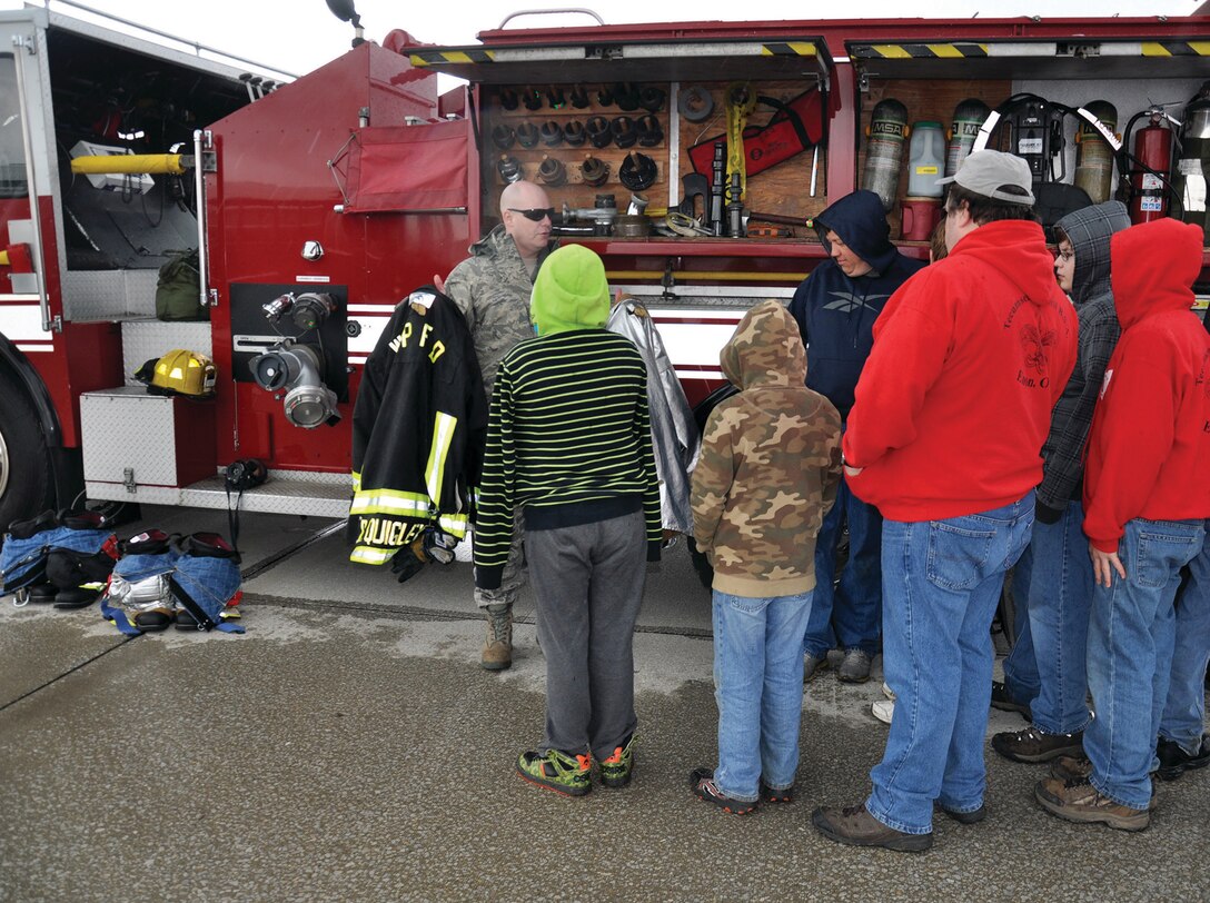 WRIGHT-PATTERSON AIR FORCE BASE, Ohio - Tech. Sgt. Dale Quigley, 445th Civil Engineer Squadron firefighter, talks to Scouts attending the May 17 445th Airlift Wing Scouts Day about his firefighter gear he wears when he responds to an emergency. The 445th Airlift Wing hosted its annual Scouts Day May 17. More than 50 Boy and Cub Scouts from around the state enjoyed a morning of activities on the 445th flightline, to include a tour of a C-17 Globemaster III, base fire truck, demonstrations by 445th Security Forces Squadron and the 445th Aeromedical Evacuation Squadron. (U.S. Air Force photo/Lt. Col. Denise Kerr)