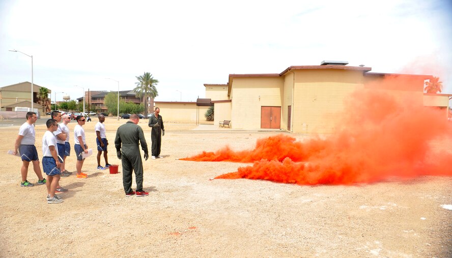 Airmen from the 56th Operations Support Squadron train Capt. Brent Ellis, 309th FS instructor pilot, and Maj. Brendan Shannon, 309th FS director of operations, on the proper use of smoke flares, which are one of the options available to signal for rescue at sea. (U.S. Air Force photo/Senior Airman Marcy Copeland)