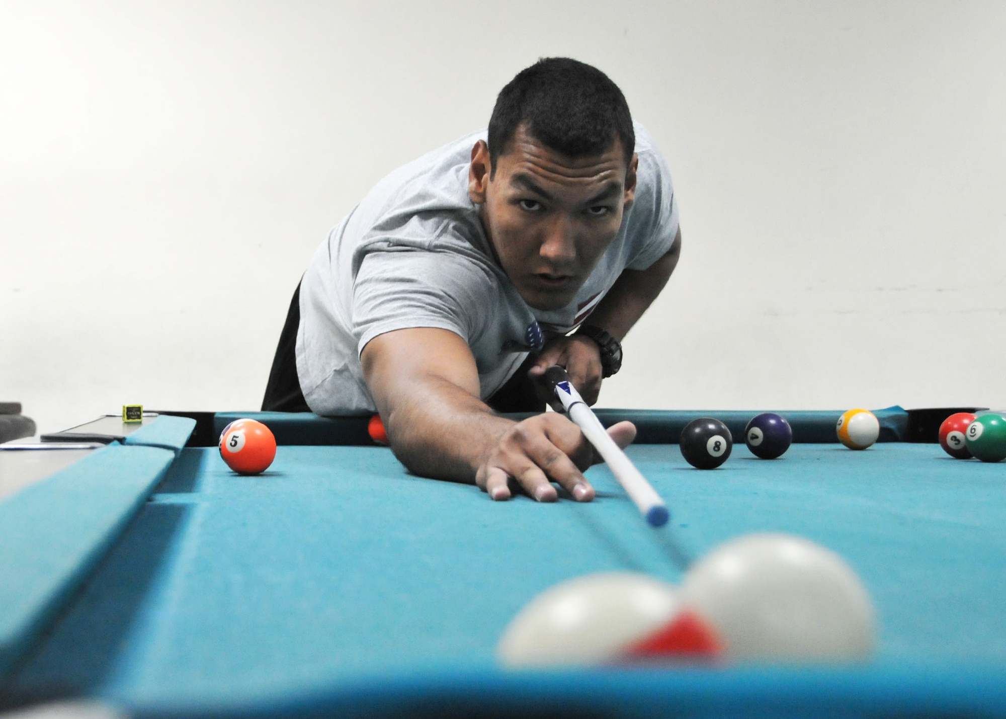 Air Force Senior Airman Troy Marquez attempts to cut the 13 ball into the corner pocket during a game of pool at the 380th Air Expeditionary Wing’s community activities center at an undisclosed location of Southwest Asia June 1, 2014.  (U.S. Air Force photo by Senior Master Sgt. Eric Peterson/Released)