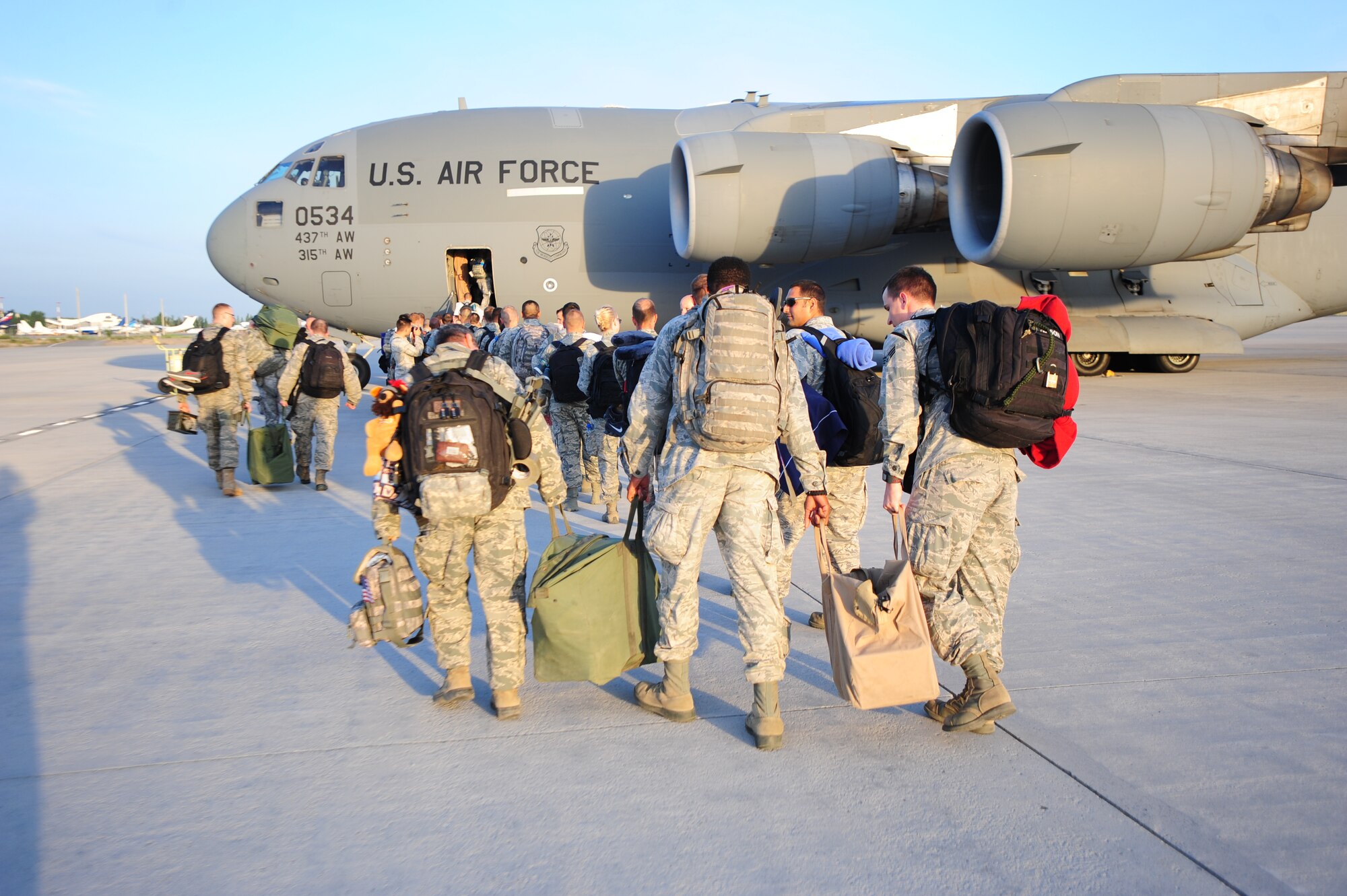 Airmen help each other with bulky equipment bags as they board a C-17 Globemaster III at Transit Center at Manas, Kyrgyzstan, June 6, 2014. The center officially ceased all operations and closed as the service members boarded two C-17s and departed from the Manas International Airport. (U.S. Air Force photo/Lt. Col. Max Despain)