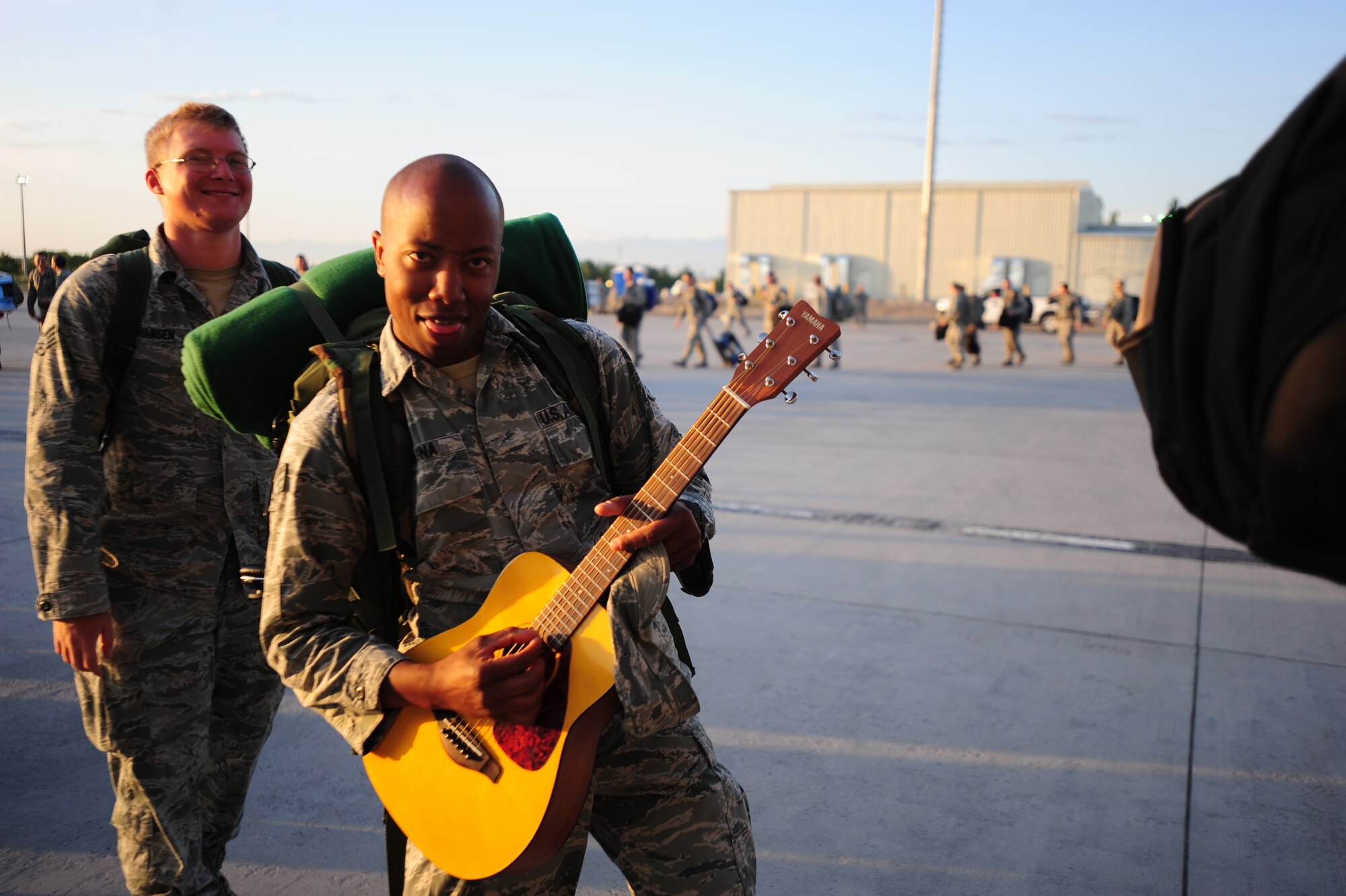 SrA Brian Maina, 376th Expeditionary Civil Engineer Squadron Security Escort from the Transit Center at Manas, Kyrgyzstan, mimics playing his guitar in joy as he boards a C-17 Globemaster III on the first leg of his journey home on June 6, 2014.  Maina joins more than 5.3 million passengers who passed through the center over the 12.5 years of its operations. (U.S. Air Force photo/Lt. Col. Max Despain)