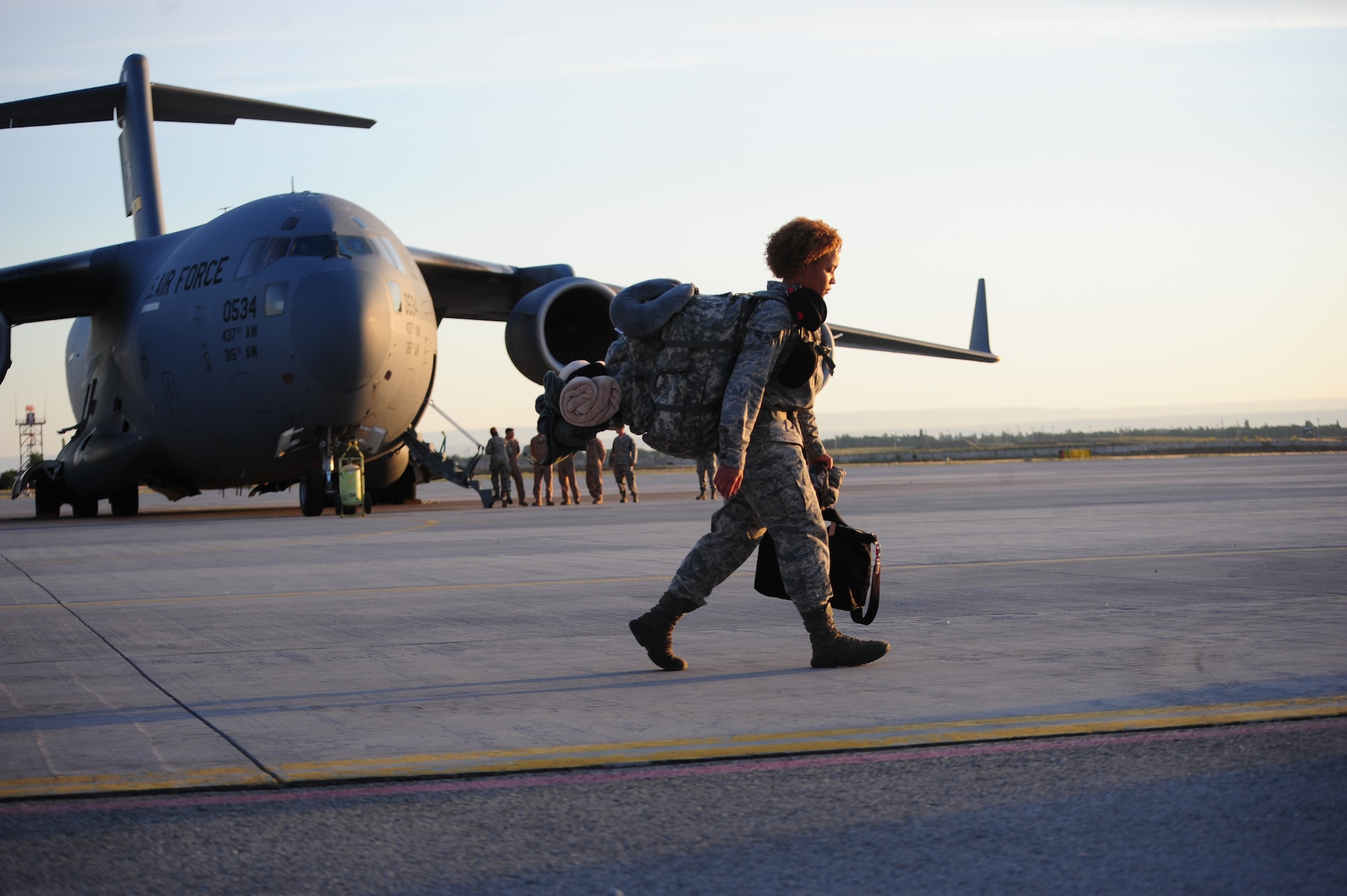 An Airman hustles to join her peers and prepare to board a C-17 Globemaster III for the first leg of her jouney home on June 6, 2014.  The “Last of the Liberandos” shut down the Transit Center at Manas, Kyrgyzstan  transferring control of the facility to the Kyrgyz government. (U.S. Air Force photo/Lt. Col. Max Despain)