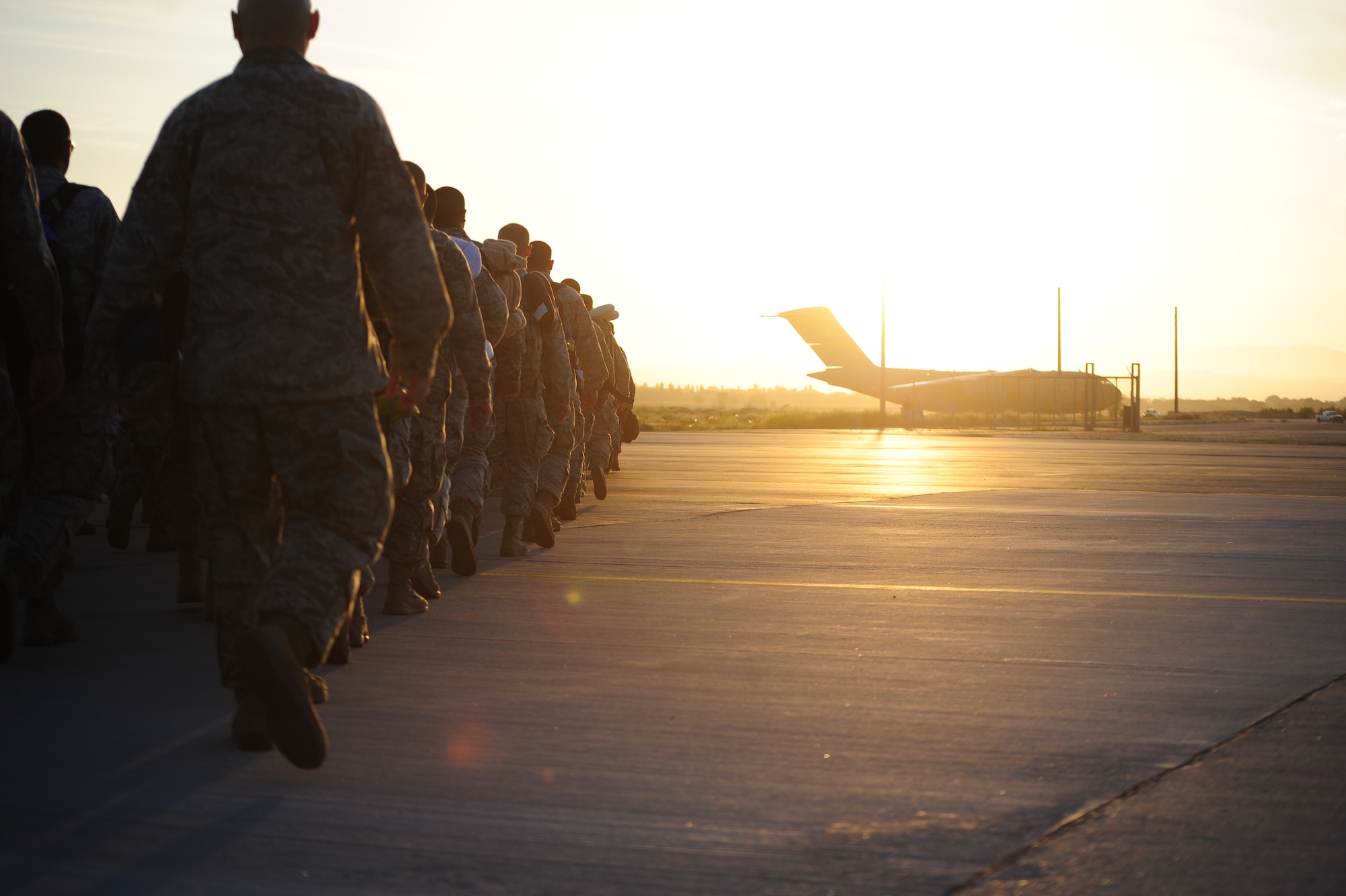 The last of the 376th  Air Expeditionary Wing Liberandos marches towards a C-17 Globemaster III waiting to fly 143 of them on the first leg of their journey home on June 6, 2014.  Normally the more than 5.3 million passengers who passed through the Transit Center at Manas, Kyrgyzstan, over the past 12.5 years would have made this journey by bus.  With ended contracts and less equipment, the final service members made their way on foot. (U.S. Air Force photo/Lt. Col. Max Despain)