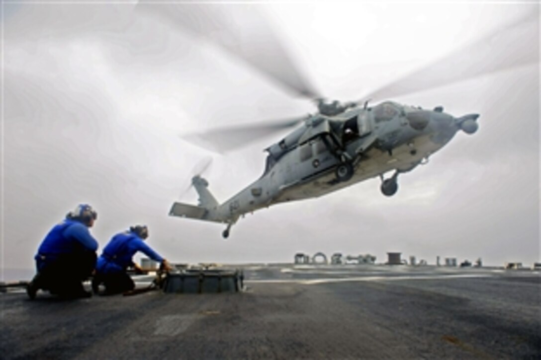 U.S. Navy sailors prepare to chain down an incoming helicopter on the the guided-missile destroyer USS John S. McCain in the Philippine Sea, June 9, 2014. The McCain is on patrol with the George Washington Carrier Strike Group supporting security and stability in the Indo-Asia-Pacific region. The helicopter is assigned to Helicopter Sea Combat Squadron 12.