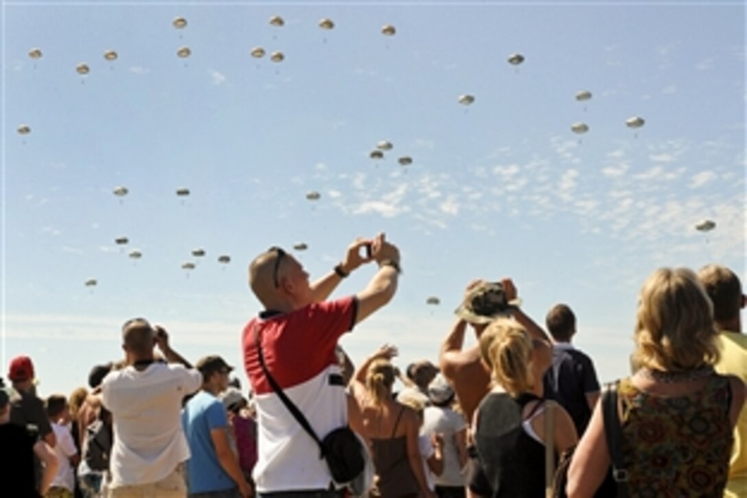 Thousands of people photograph U.S. and international paratroopers as they land in the Normandy  region of France, June 8, 2014, to commemorate the 70th anniversary of D-Day. More than 700 paratroopers from the United States, France, Germany, England and the Netherlands re-enacted the historic airdrop over the town of Chef-du-Pont, France.