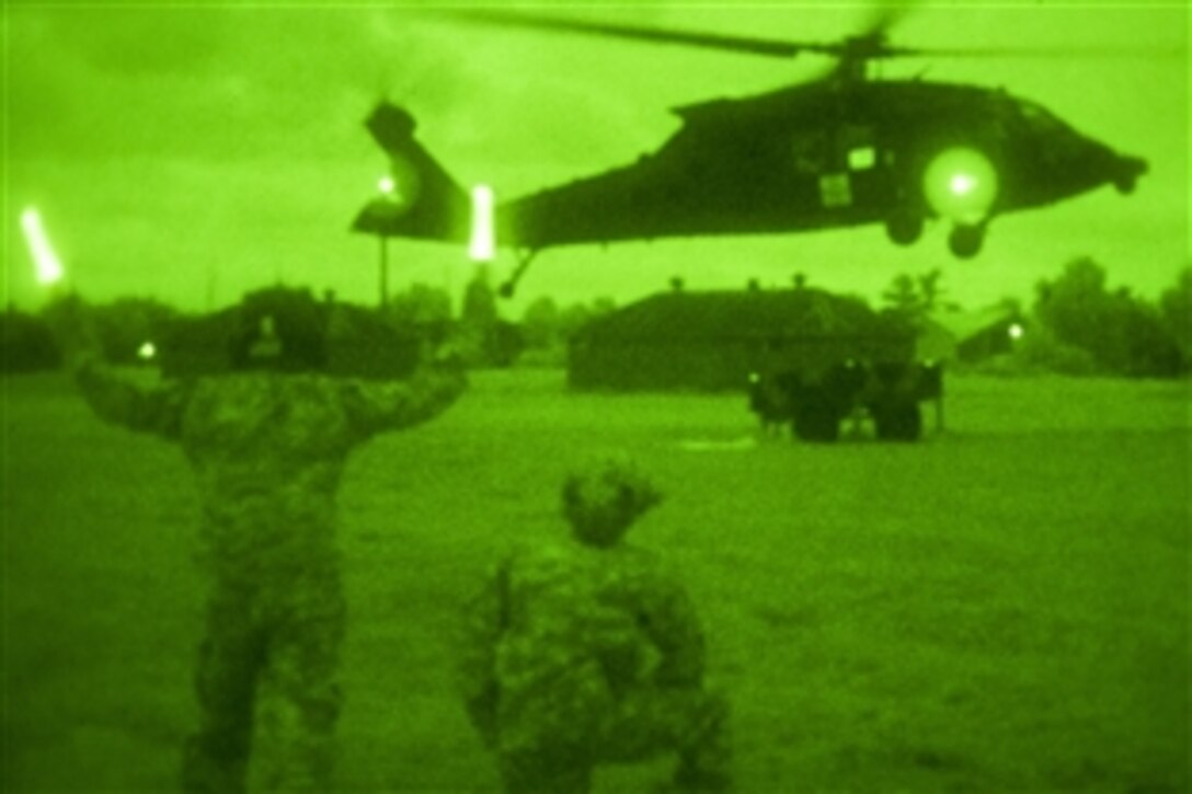 As seen through a night-vision device, U.S. Army Sgt. 1st Class Louis Lawton guides a UH-60 Black Hawk helicopter during slingload training on Camp Johnson in Colchester, Vt., June 5, 2014. Lawton is assigned to Company C, 3rd Battalion, 126th Aviation Regiment, Massachusetts Army National Guard.