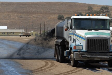 California Army National Guard engineers spray an even coat of black dye across the completed surface of Camp Roberts' recently restabilized parade field April 29, 2014. 