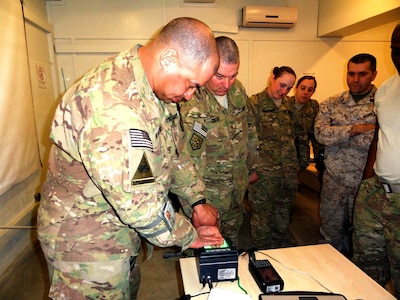 Army Maj. James Collie guides his student Army Staff Sgt. Joseph Ri'chard through a practical exercise of fingerprinting during his criminal justice class here at Camp Phoenix.