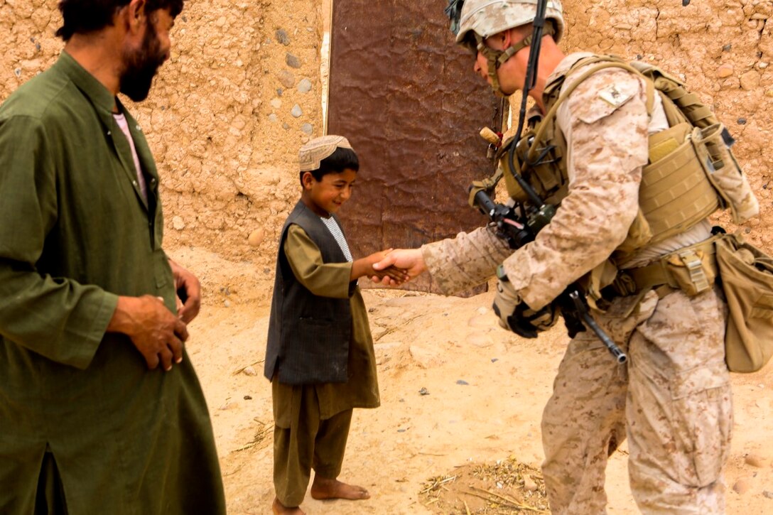 Corporal George Lynch, a native of Seaford, New York, shakes hands with a local Afghan child during a reconnaissance patrol near Patrol Base Boldak in Helmand province, Afghanistan, May 15, 2014. Lynch, a squad leader with Charlie Company, 1st Battalion, 2nd Marine Regiment, conducts daily patrols in order to maintain trust and communication with the local Afghan population. (U.S. Marine Corps Photo by Cpl Michael Dye/Released)