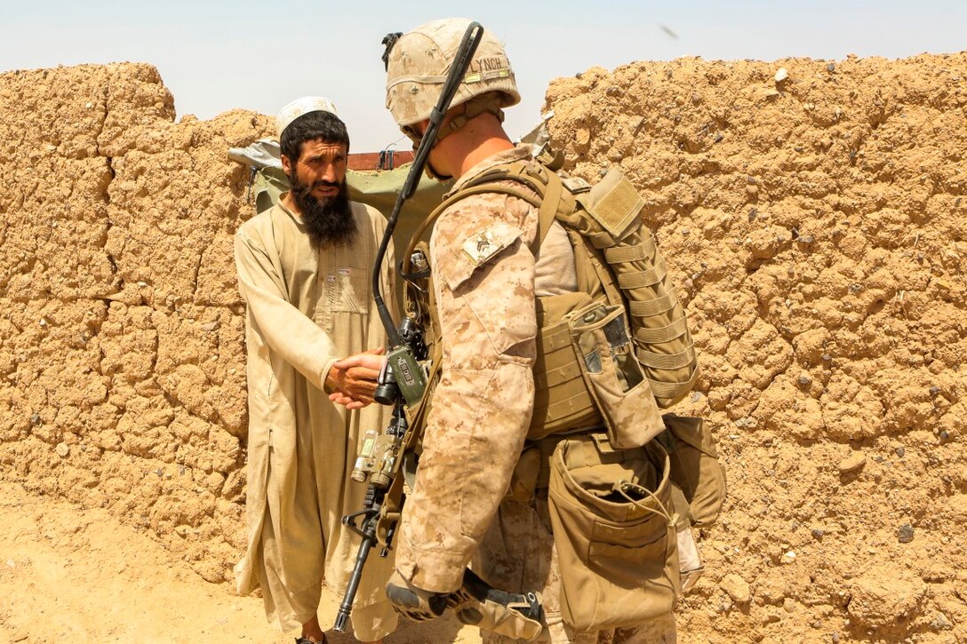 Corporal George Lynch, a native of Seaford, New York, shakes hands with a local Afghan villager during a reconnaissance patrol near Patrol Base Boldak in Helmand province, Afghanistan, May 15, 2014.  Lynch, a squad leader with Charlie Company, 1st Battalion, 2nd Marine Regiment, along with Marines and sailors of the unit conduct daily patrols in order to maintain trust and communication with the local Afghan population.   (U.S. Marine Corps Photo by Cpl Michael Dye/Released)