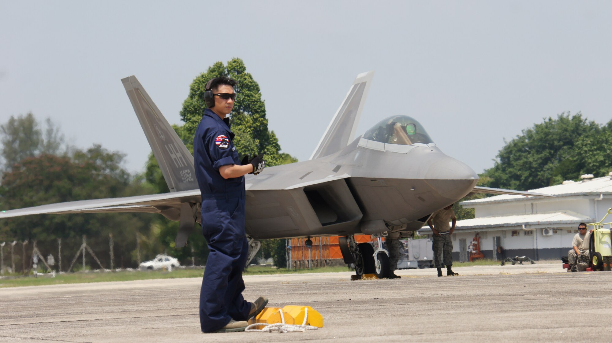 Tech. Sgt. Russel Mesinas, maintainer with the Hawaii National Guard’s 154th Wing, waits for a taxiing F-22 Raptor at the final safety check before take off in the first day of flying for Cope Taufan 2014,  P.U. Butterworth, Malaysia, June 9, 2014.  Cope Taufan is designed to improve U.S. and Malaysian combined readiness and interoperability. Cope Taufan reinforces U.S. Pacific Command Theater Security Cooperation goals for the Southeast Asian region and demonstrates U.S. capability to project forces strategically in a combined, joint environment. More than 450 Airmen are participating, as well as four U.S. Air Force airframes, which includes the inaugural deployment of the F-22 Raptor to a Southeast Asian exercise. (U.S. Air Force photo by Tech. Sgt. Andrew Jackson/Released)